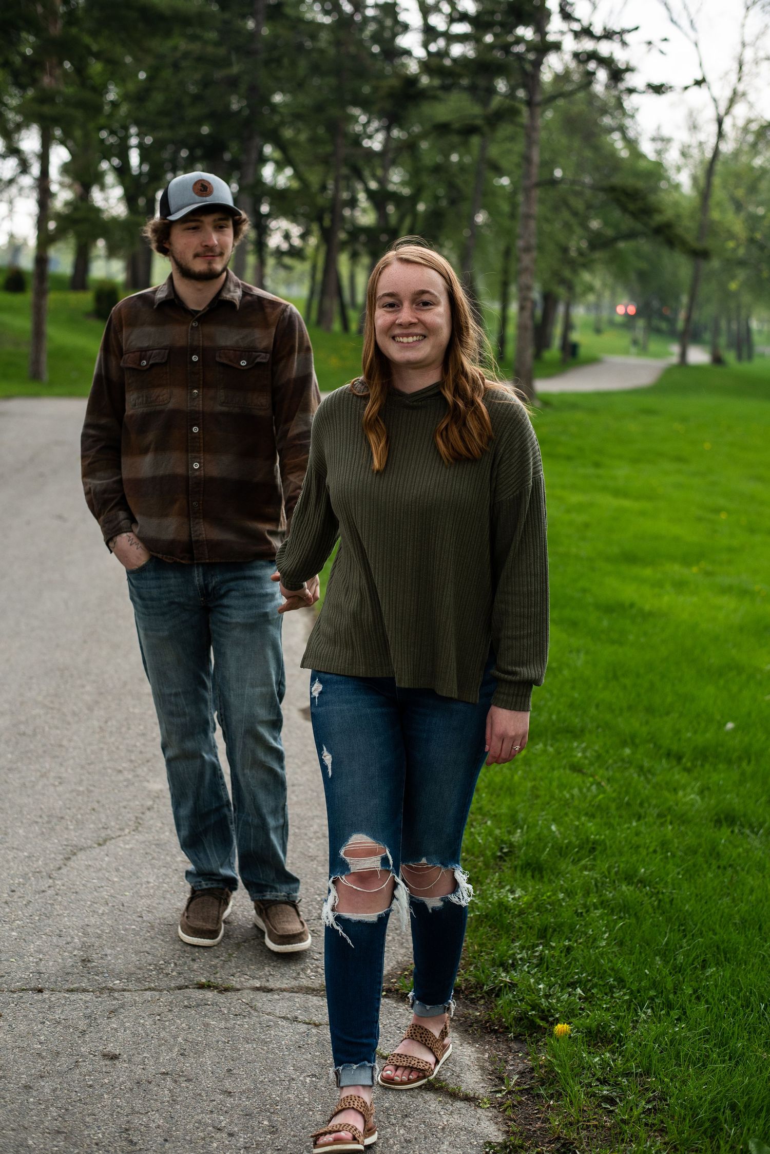 Couple takes a casual stroll together on a path through a green park setting.