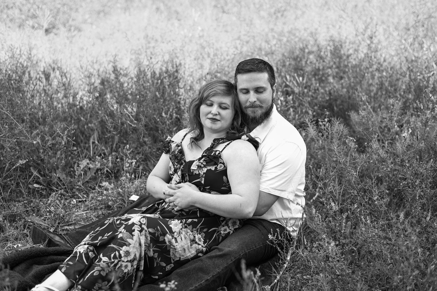 A romantic couple embraces in black and white photos taken during an outdoor photo session.