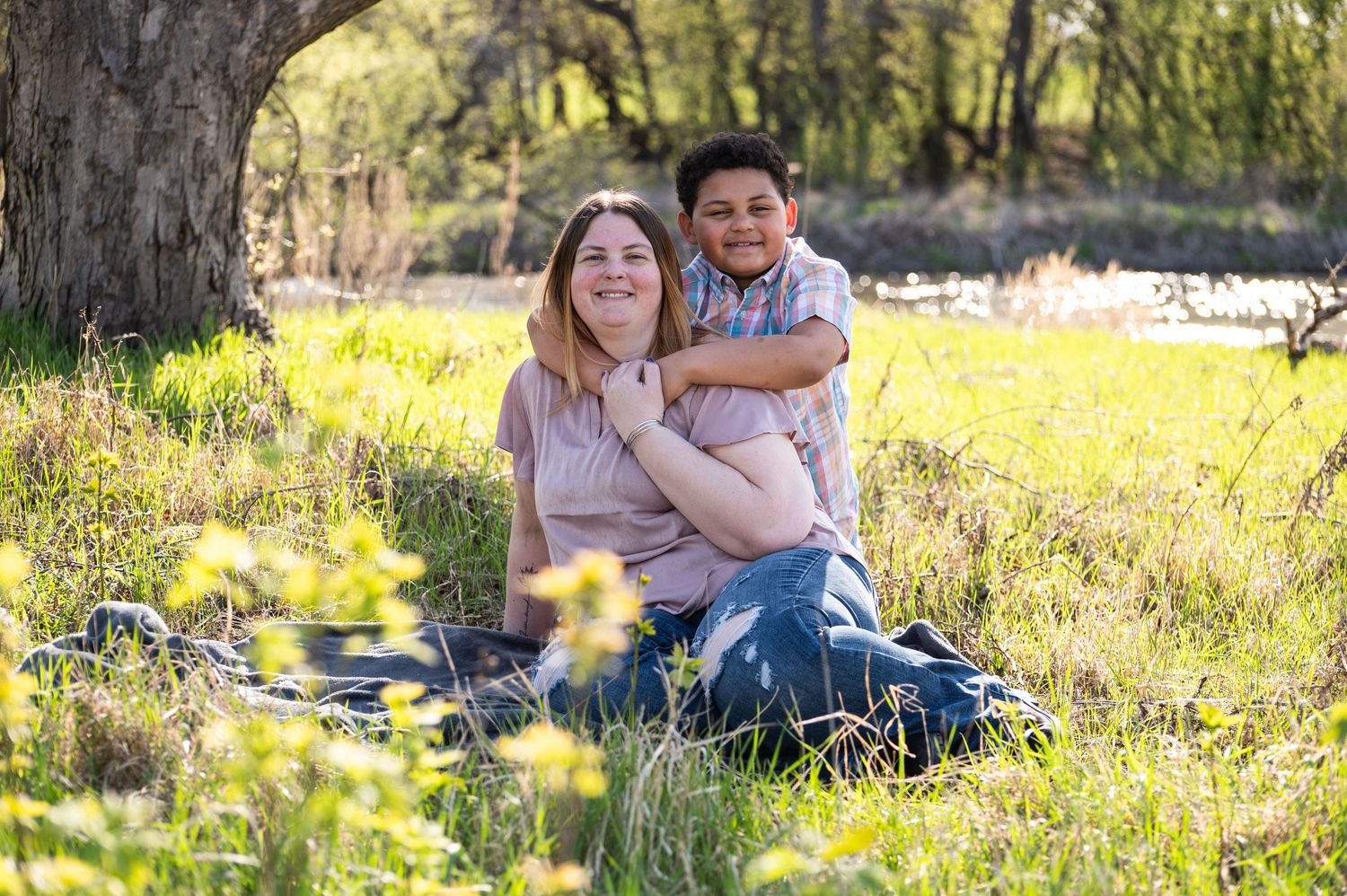 Casual outdoor portrait session on grassy hill with natural lighting.