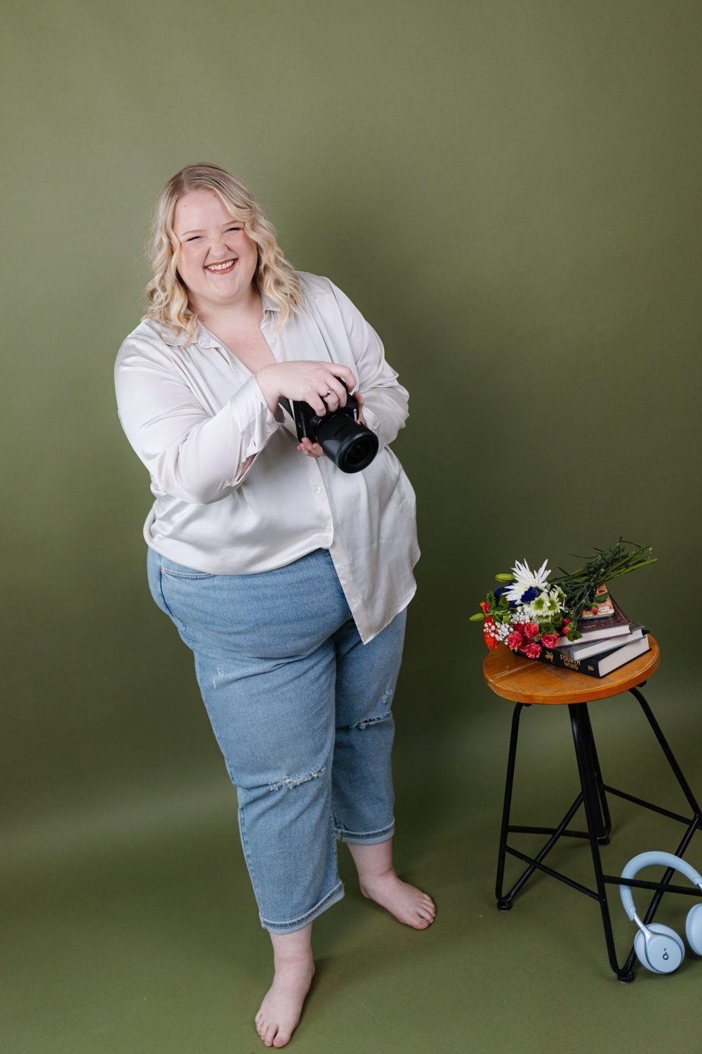 Charli laughing with her camera against an olive backdrop