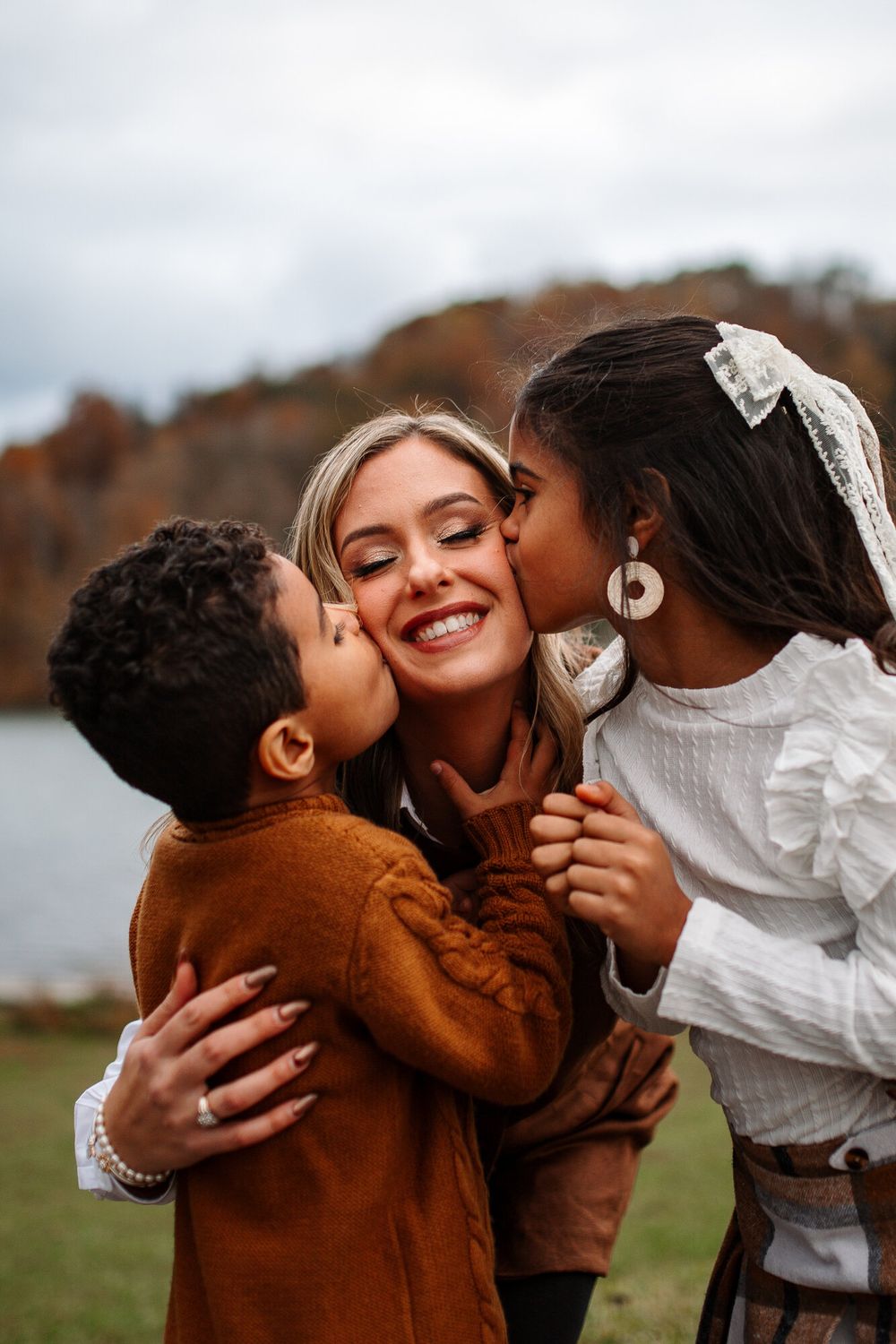 Two children kissing their mom's cheeks during a fall family session