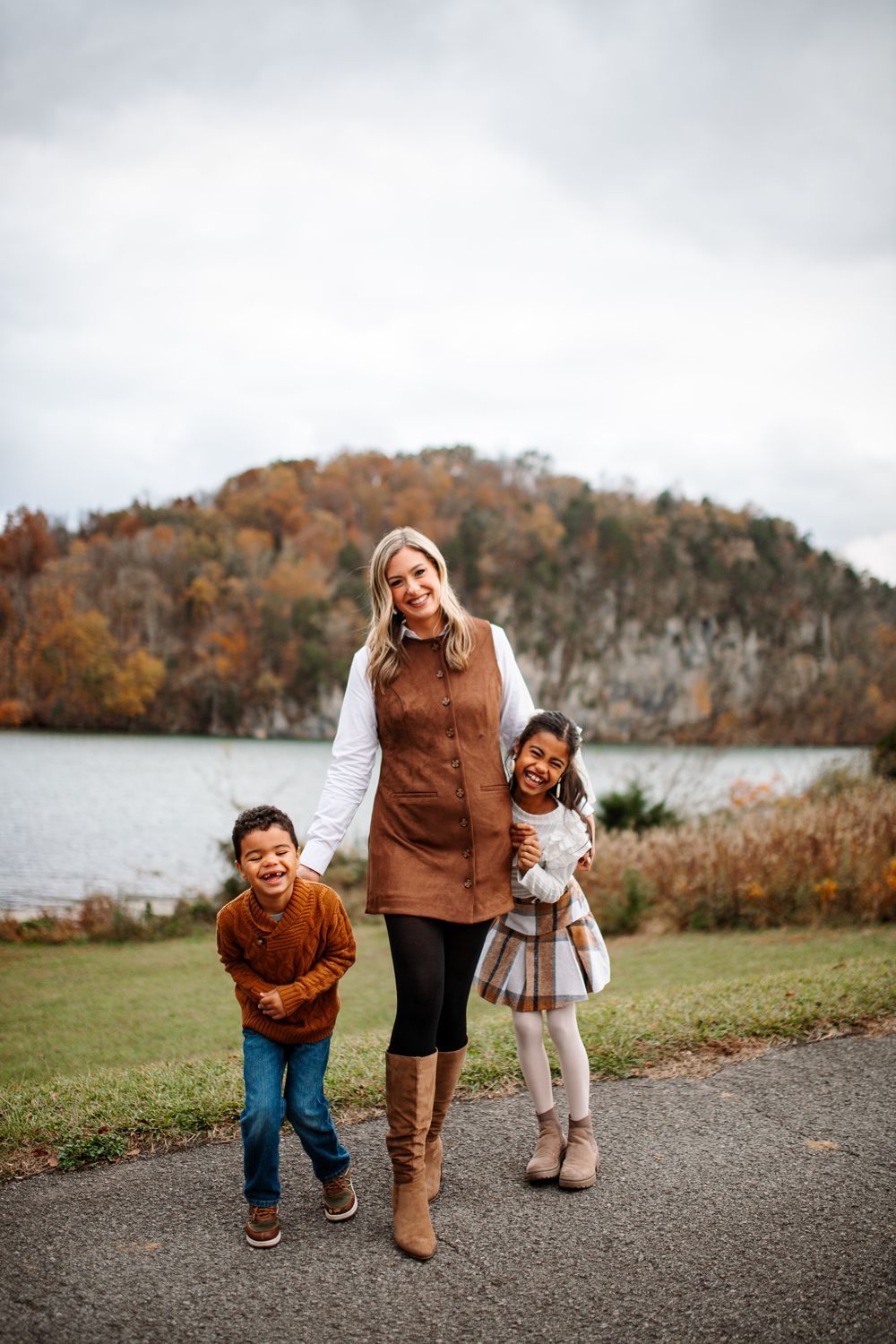 Mom laughing with her two kids by the lake in fall