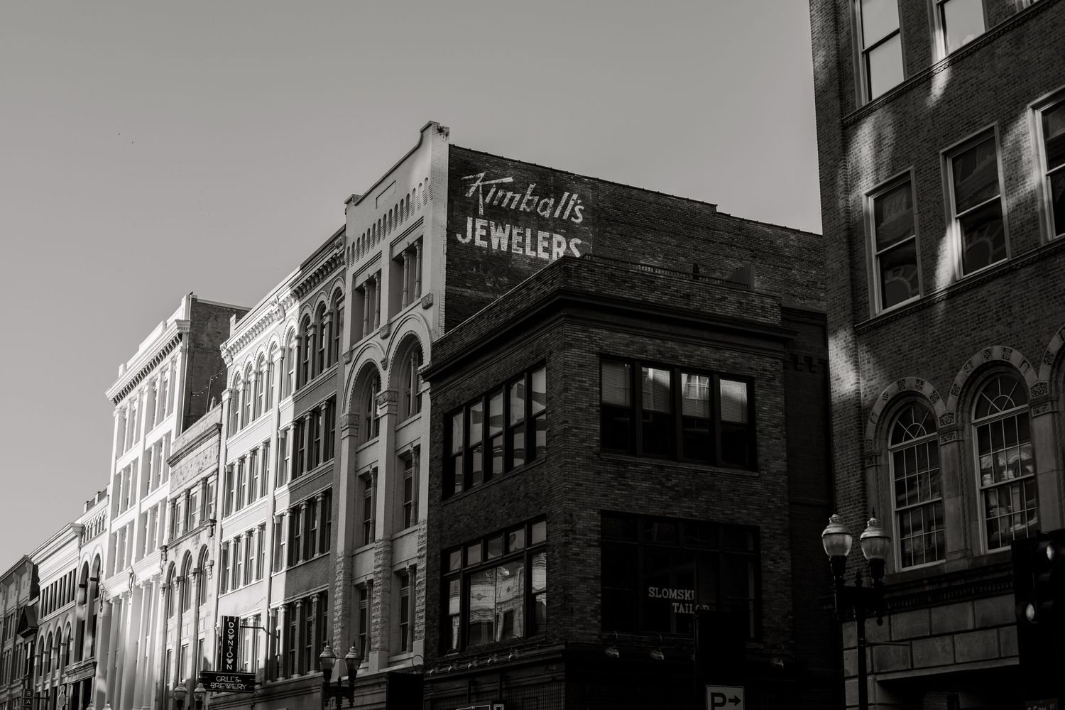 Black and white photo of historic downtown brick buildings with a vintage Kimball's Jewelers sign and ornate arched windows.