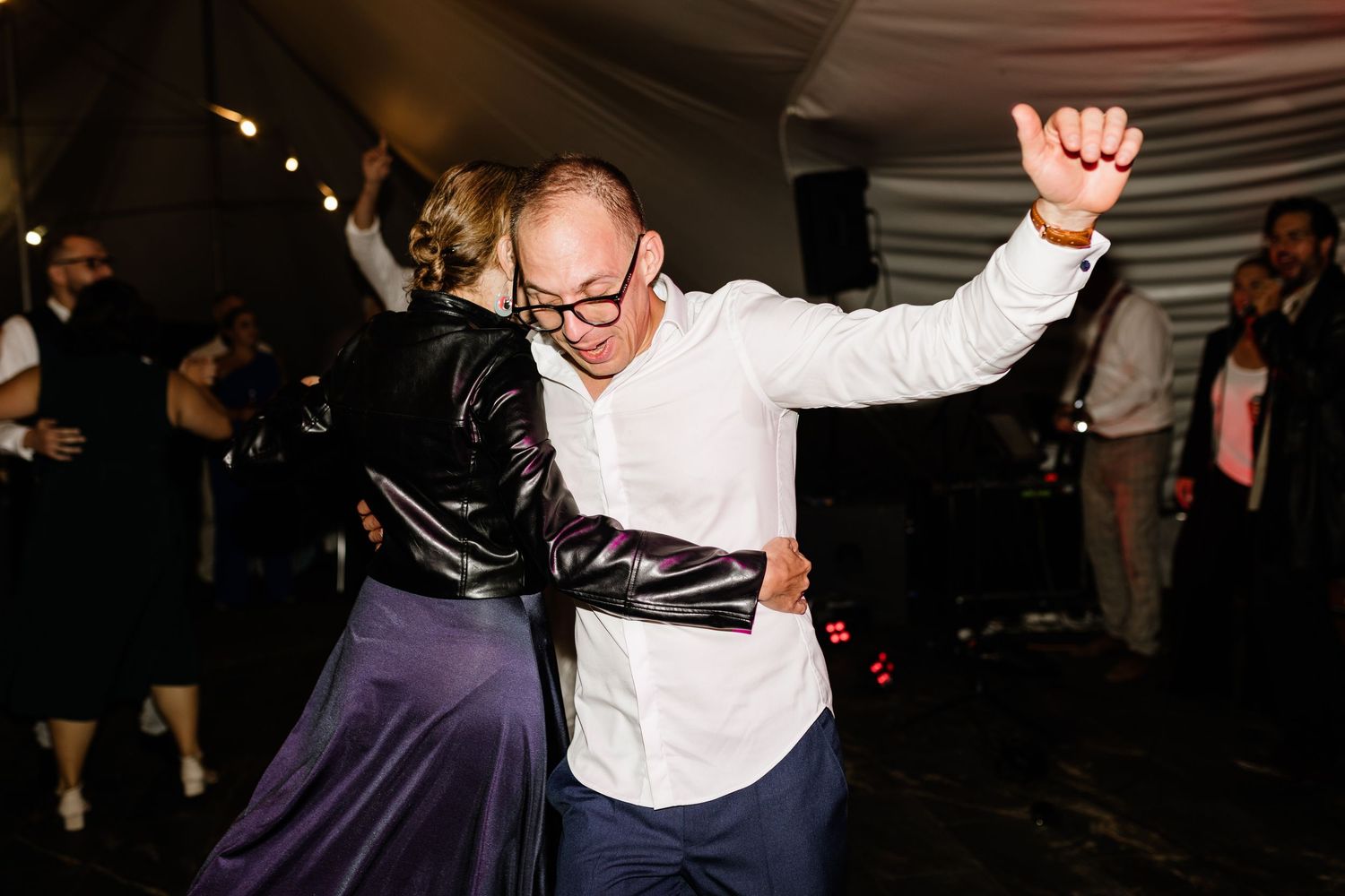 Couple dancing energetically together on a crowded wedding reception dance floor.
