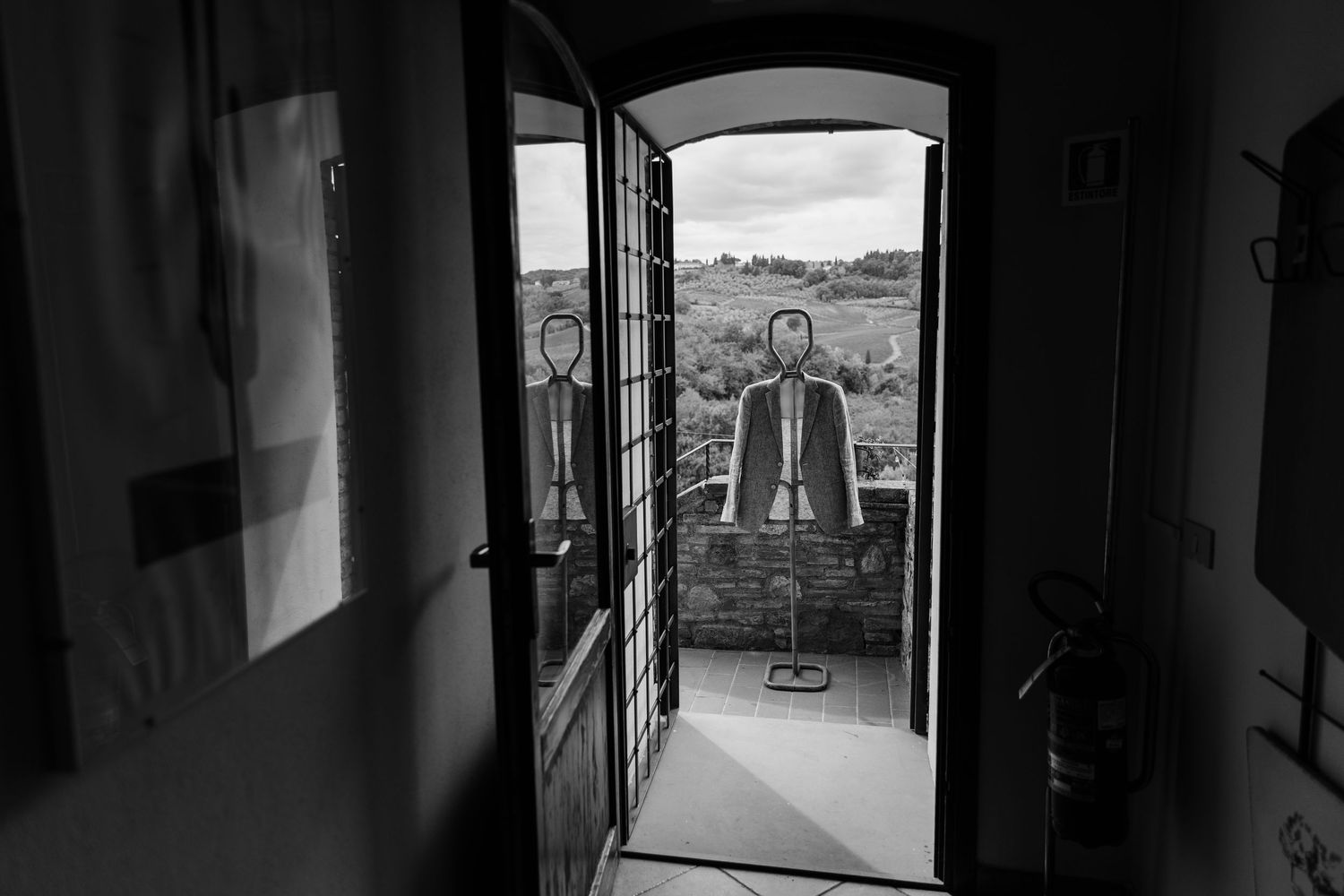 Black and white photo of a person standing in an open doorway overlooking a rural landscape.