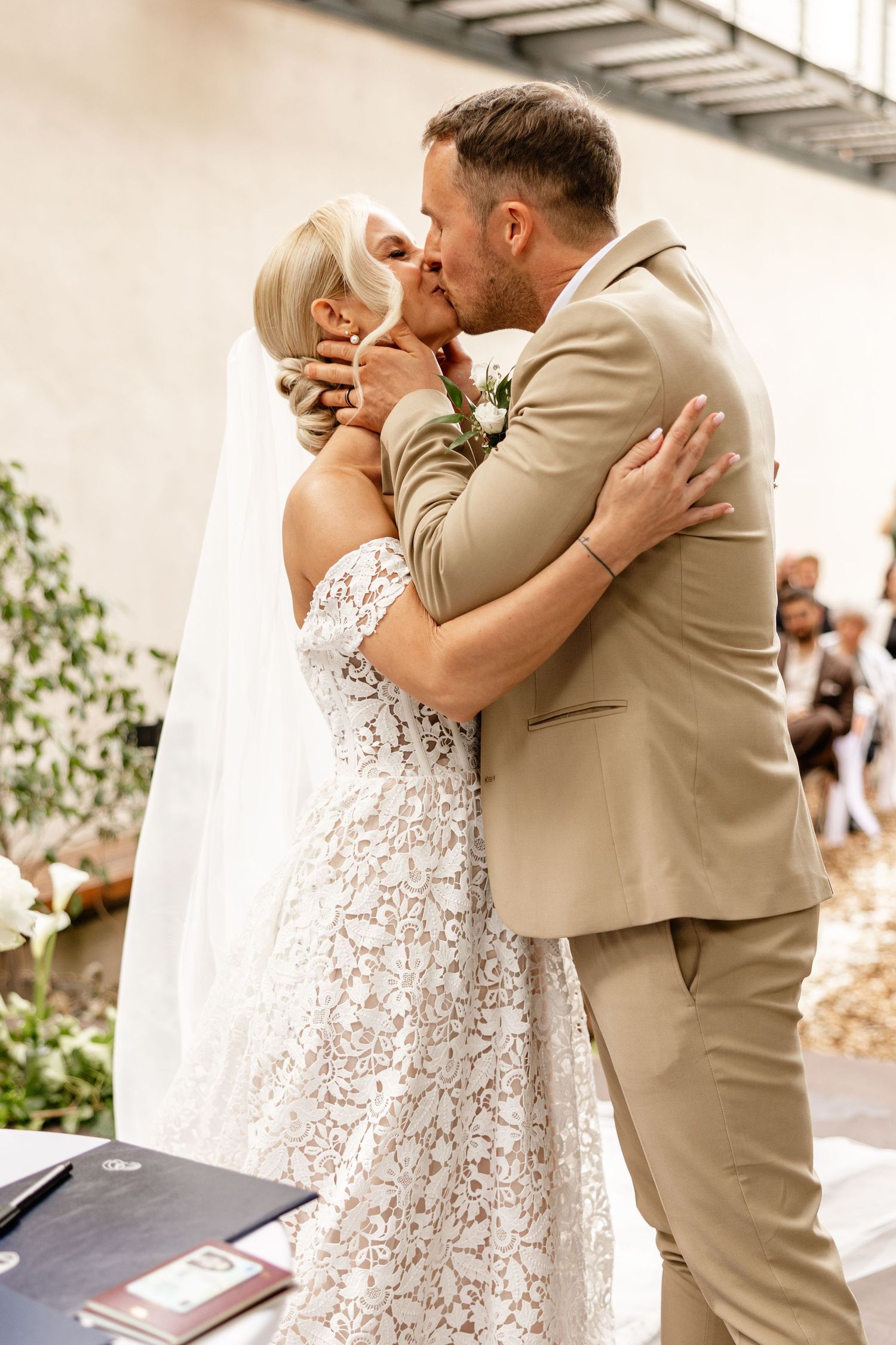 Bride and groom share their first kiss at the altar during an elegant indoor wedding ceremony.
