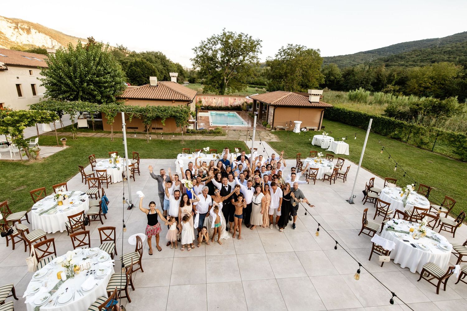 Aerial view of wedding guests gathered on patio with decorated tables at villa venue.