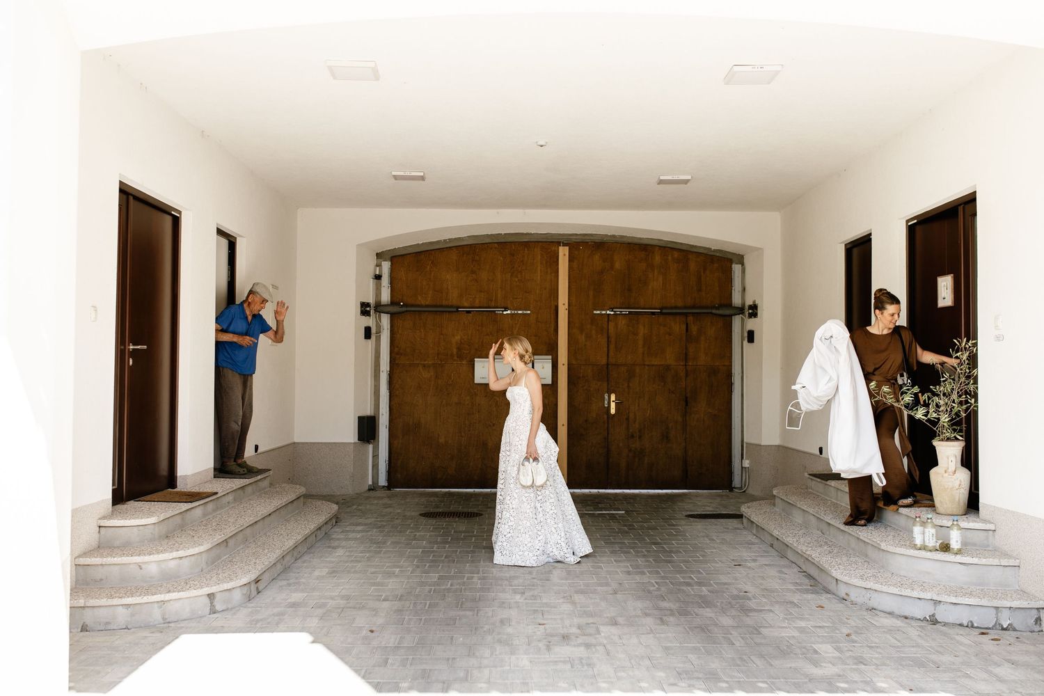 Bride and groom share a romantic moment in front of large wooden doors at an elegant white wedding venue.