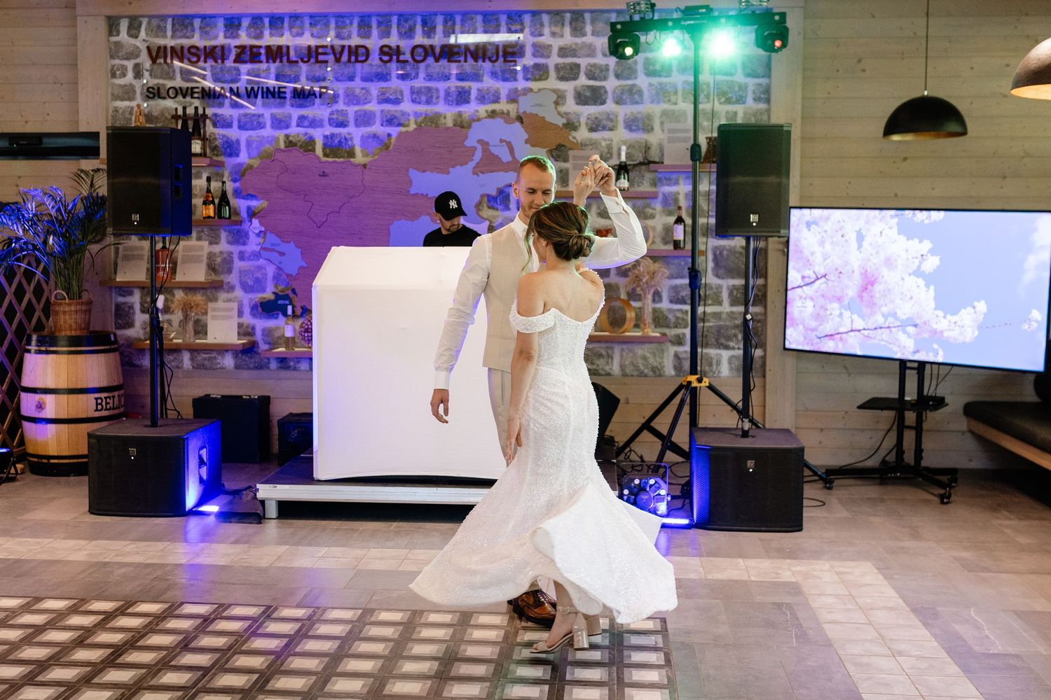 Bride and groom share their first dance at a wedding reception venue with stone walls and DJ setup.