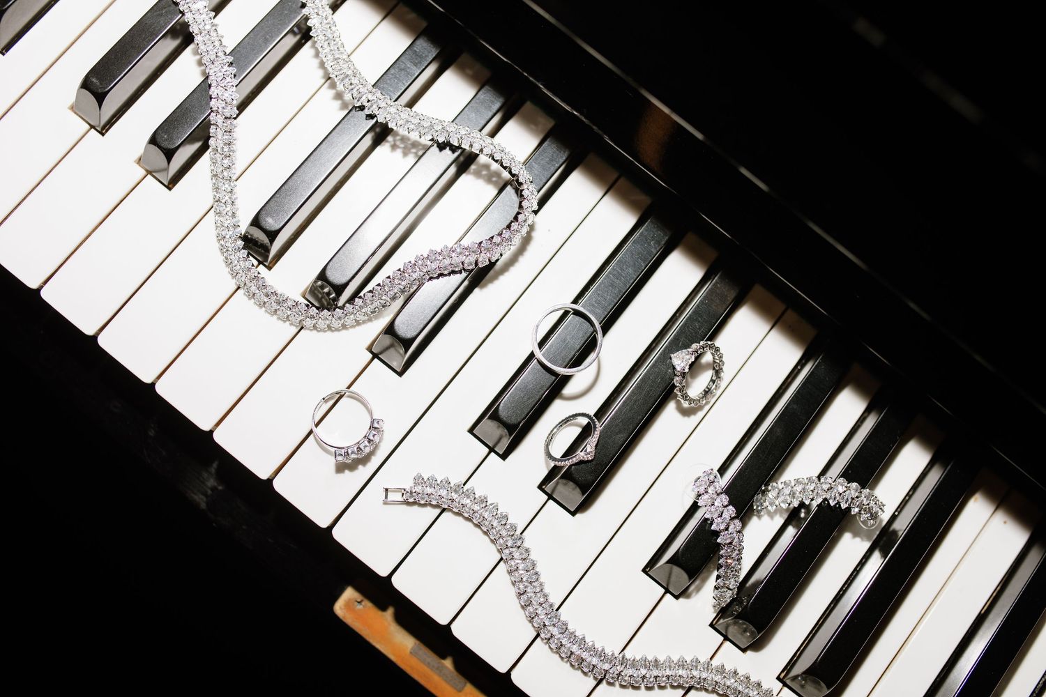 Diamond jewelry and rings elegantly arranged on black and white piano keys.