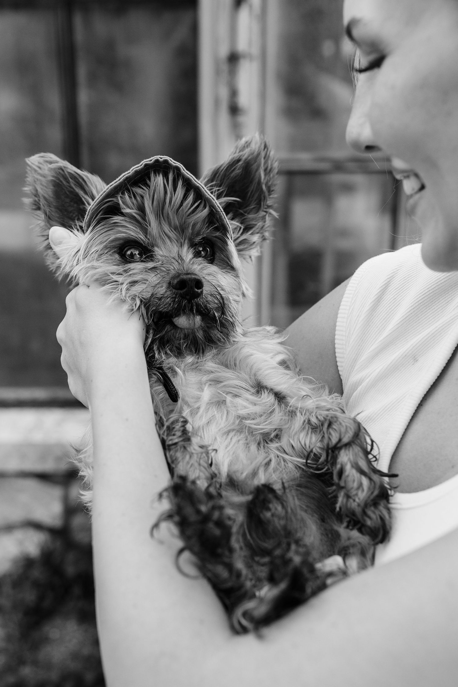 Black and white photo of a woman holding a small Yorkshire Terrier dog close to her face, smiling warmly.