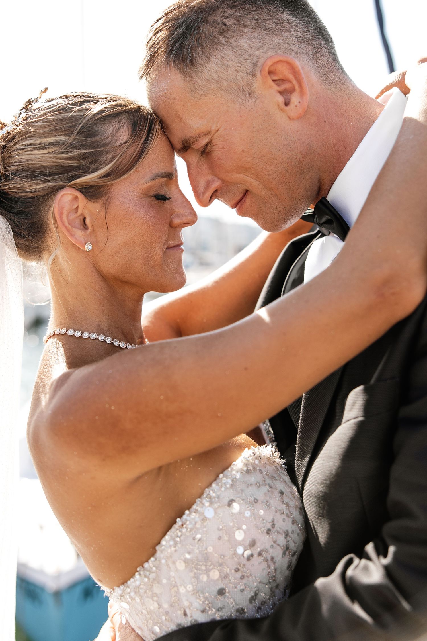 Bride and groom touching foreheads and embracing in a tender romantic wedding moment.