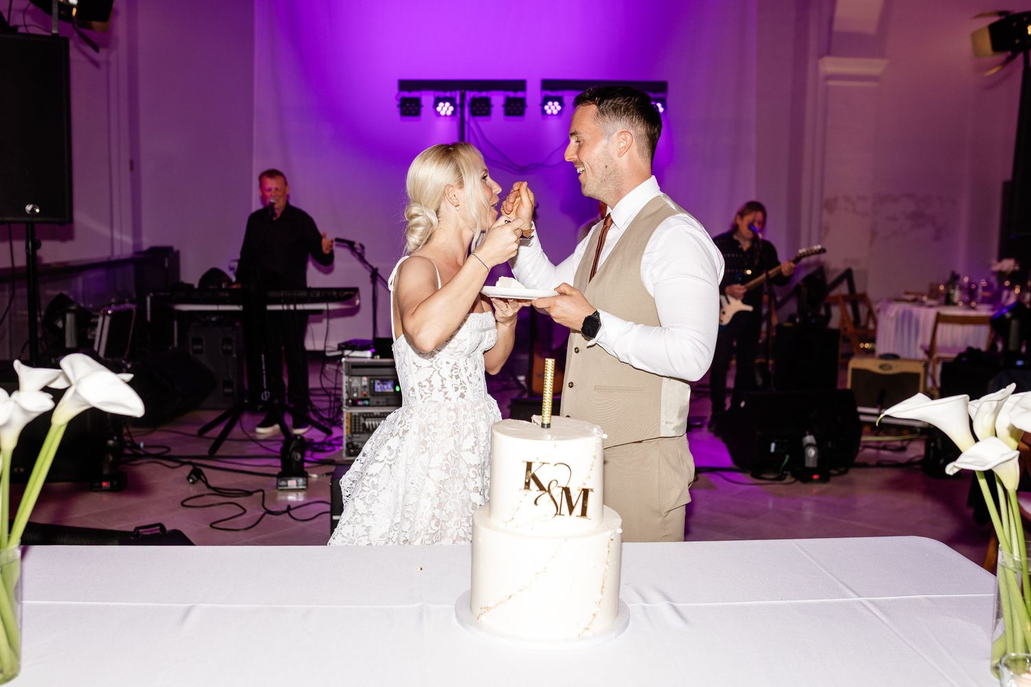 Bride and groom cut their elegant marble wedding cake together during their reception with a live band performing.