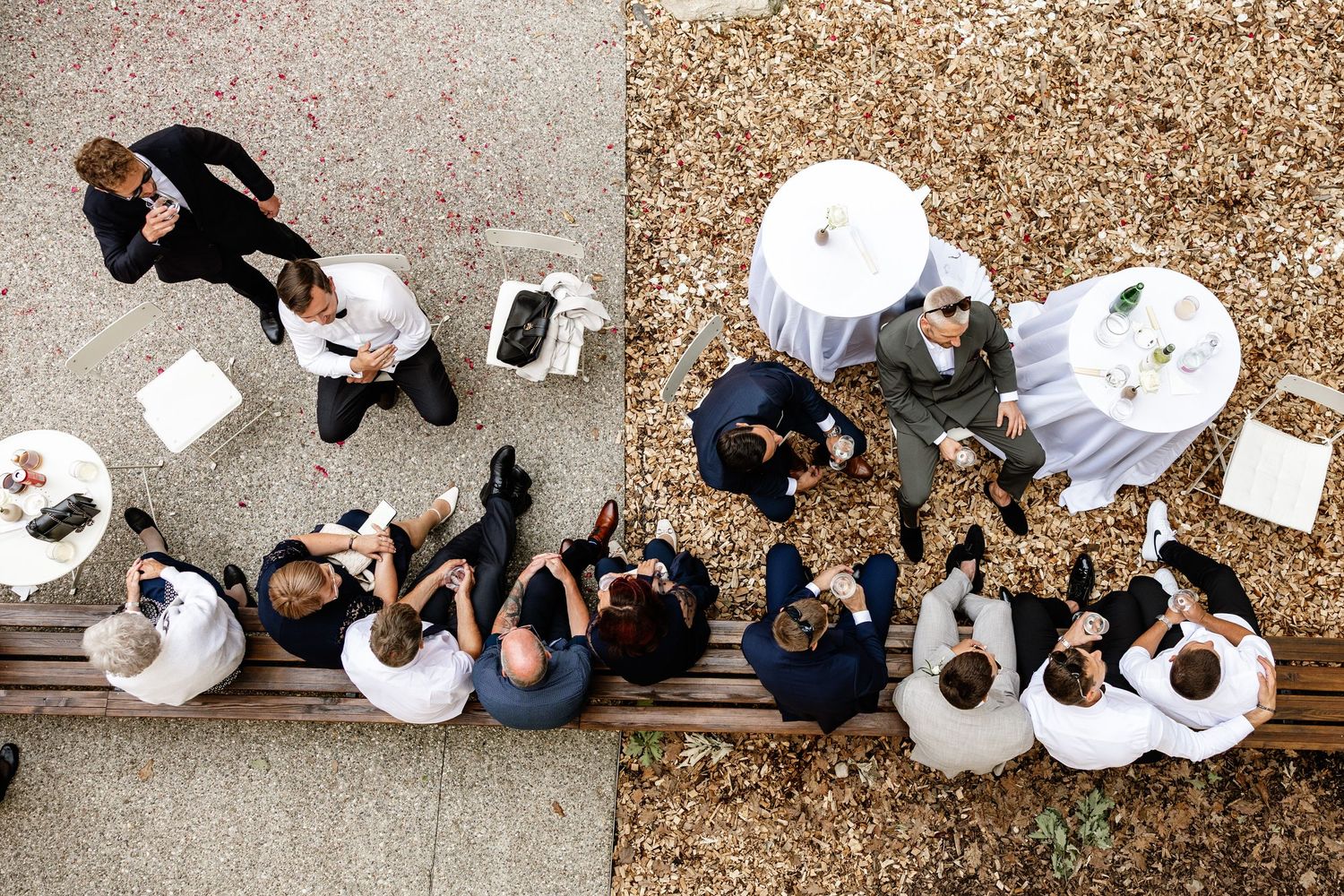 Aerial view of wedding guests mingling outdoors at elegant reception with round tables.