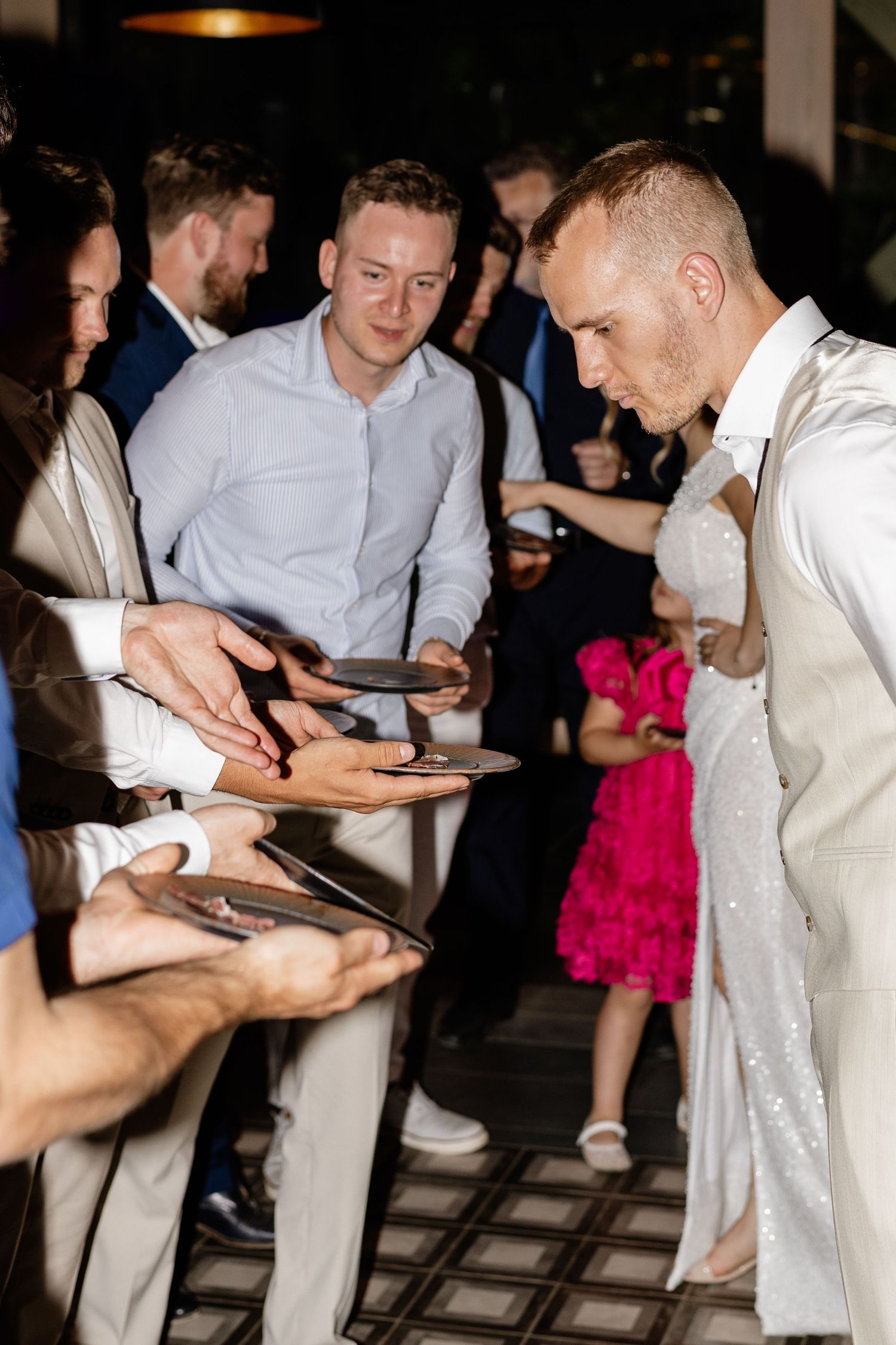 Man in white sequin suit signs autographs for fans at an indoor event.