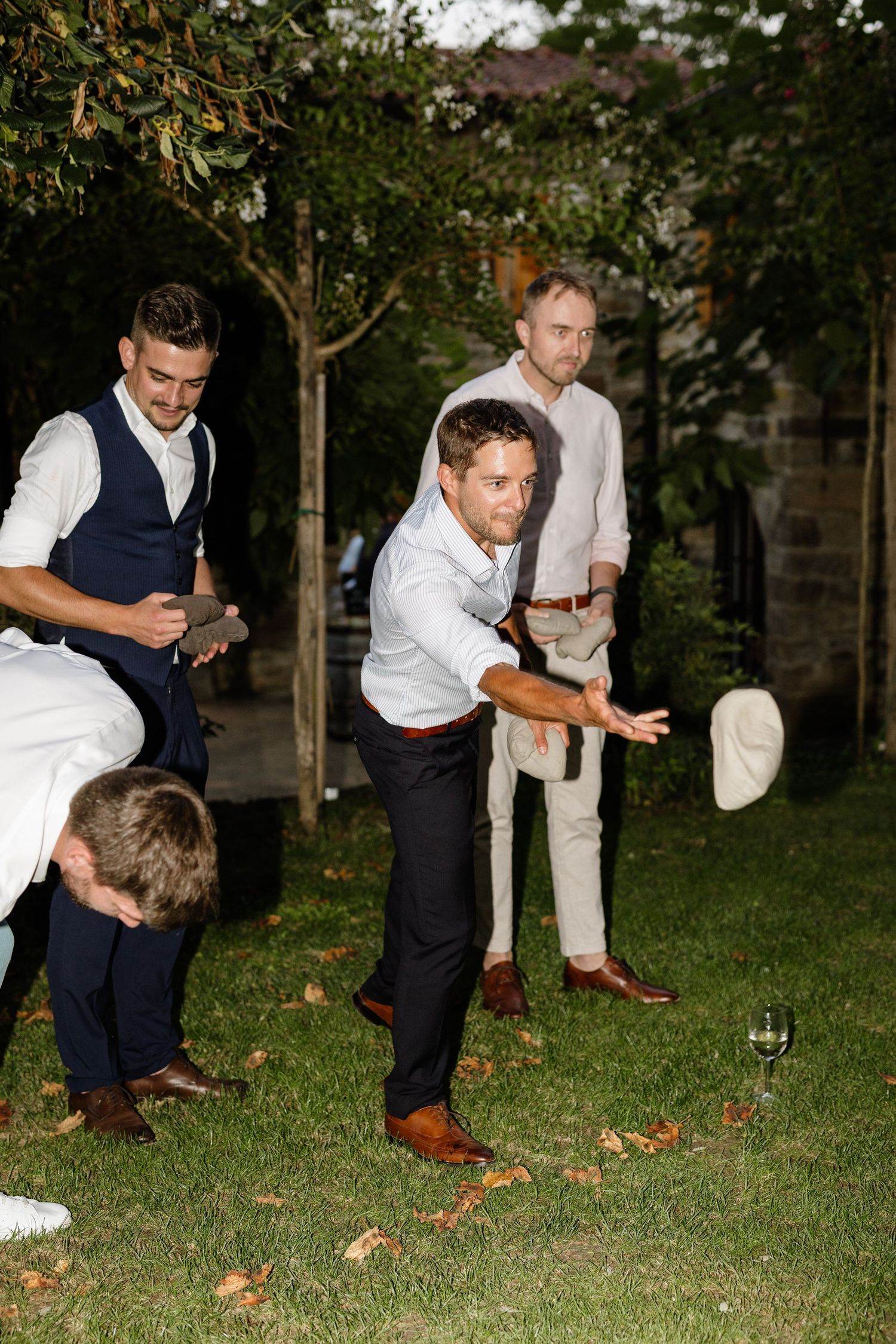 Group of men playing a lawn game in a garden at a wedding reception.