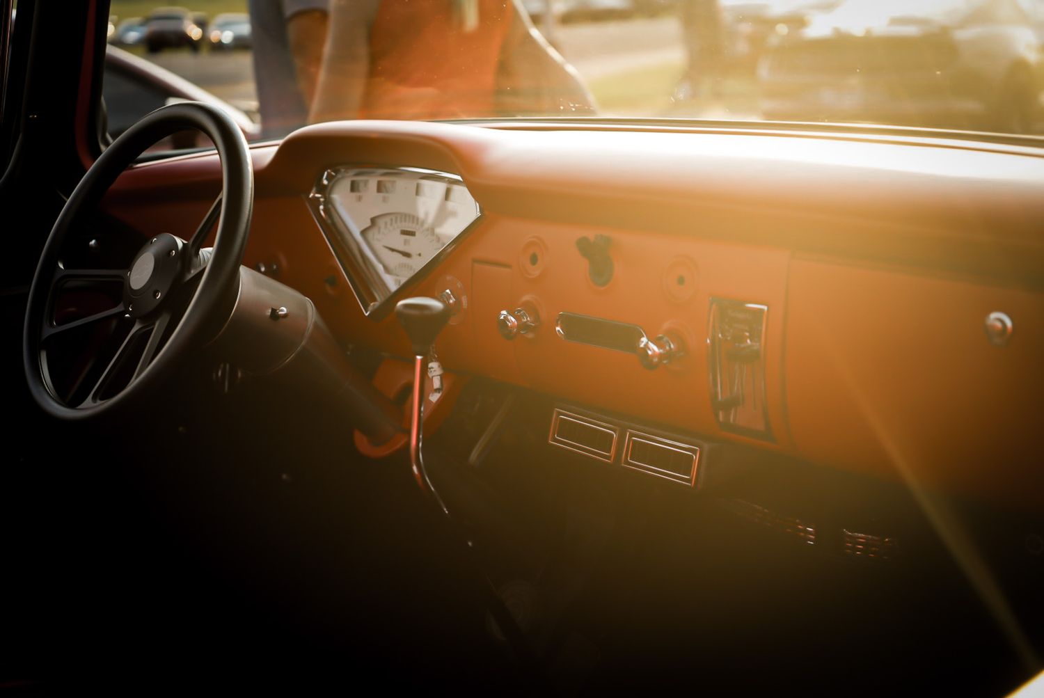 Vintage truck interior bathed in golden sunlight showcasing retro dashboard and black steering wheel. Cars & Christ