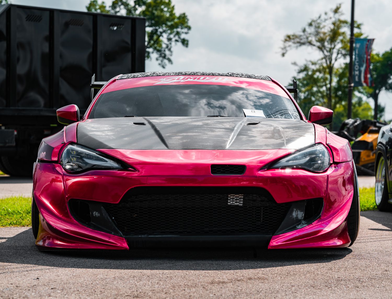 Pink chrome widebody Toyota 86 at a car show, featuring aggressive front bumper and custom body kit. Slammednuff