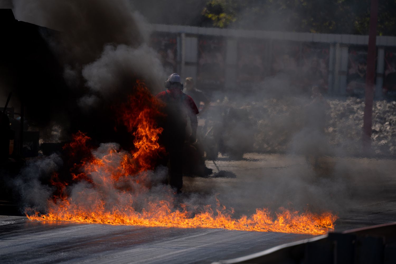 Dramatic flames and black smoke engulf a drag racing track during a burnout at a motorsport event. Sick Smokies