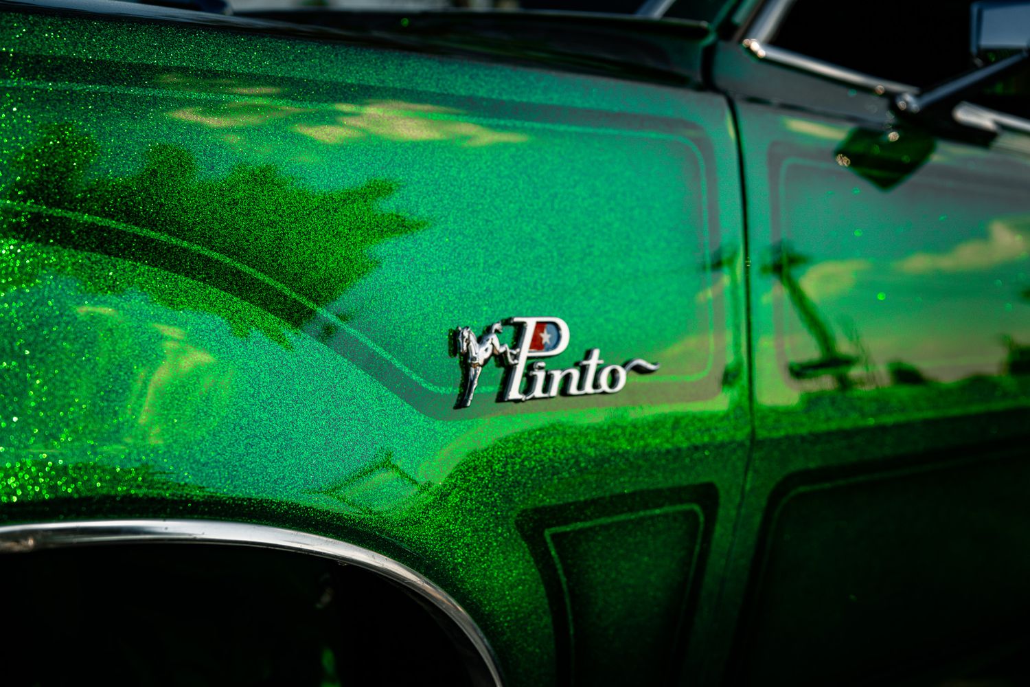 Close-up of sparkling green metallic Ford Pinto badge on a custom painted classic car at car show. Redneck Rumble