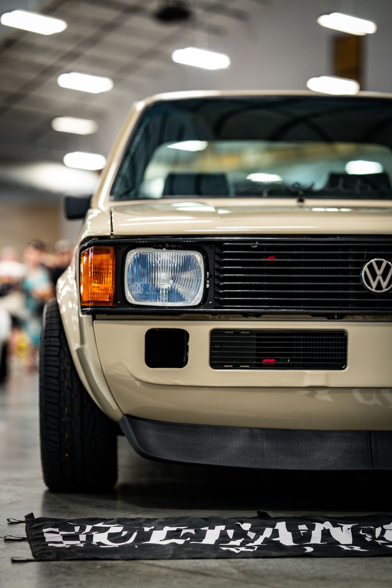 Classic cream Volkswagen Golf mk2 on display at an indoor car show with vintage styling. Slammednuff
