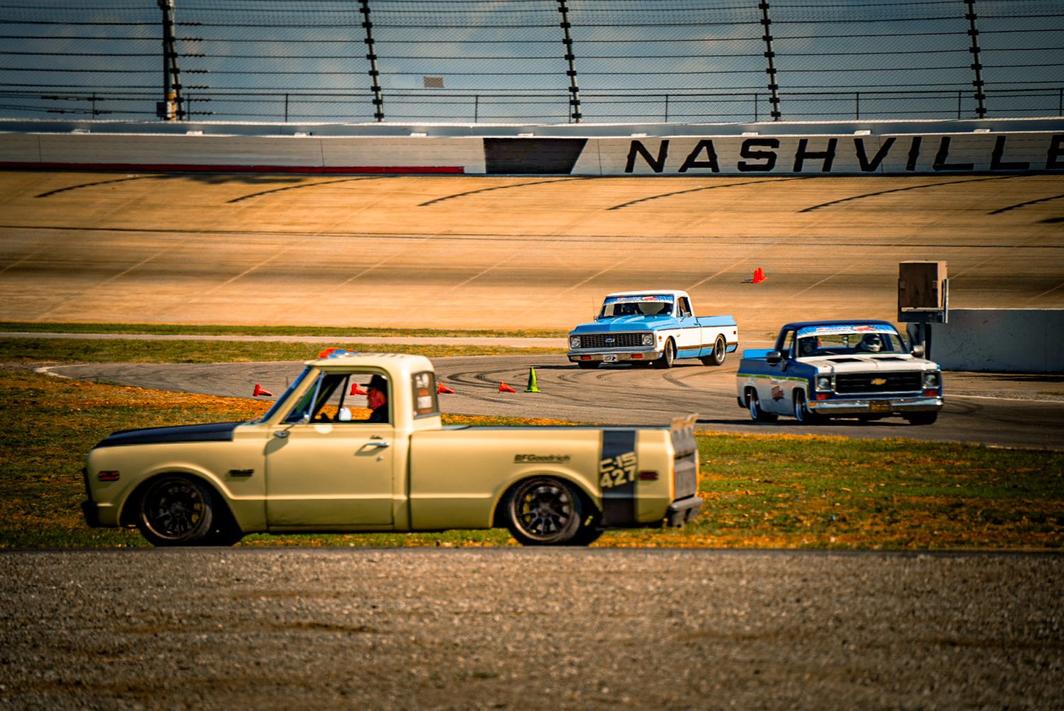 Gold lowered C10 pickup truck racing on Nashville Superspeedway track with other trucks. C10 Nationals Nashville