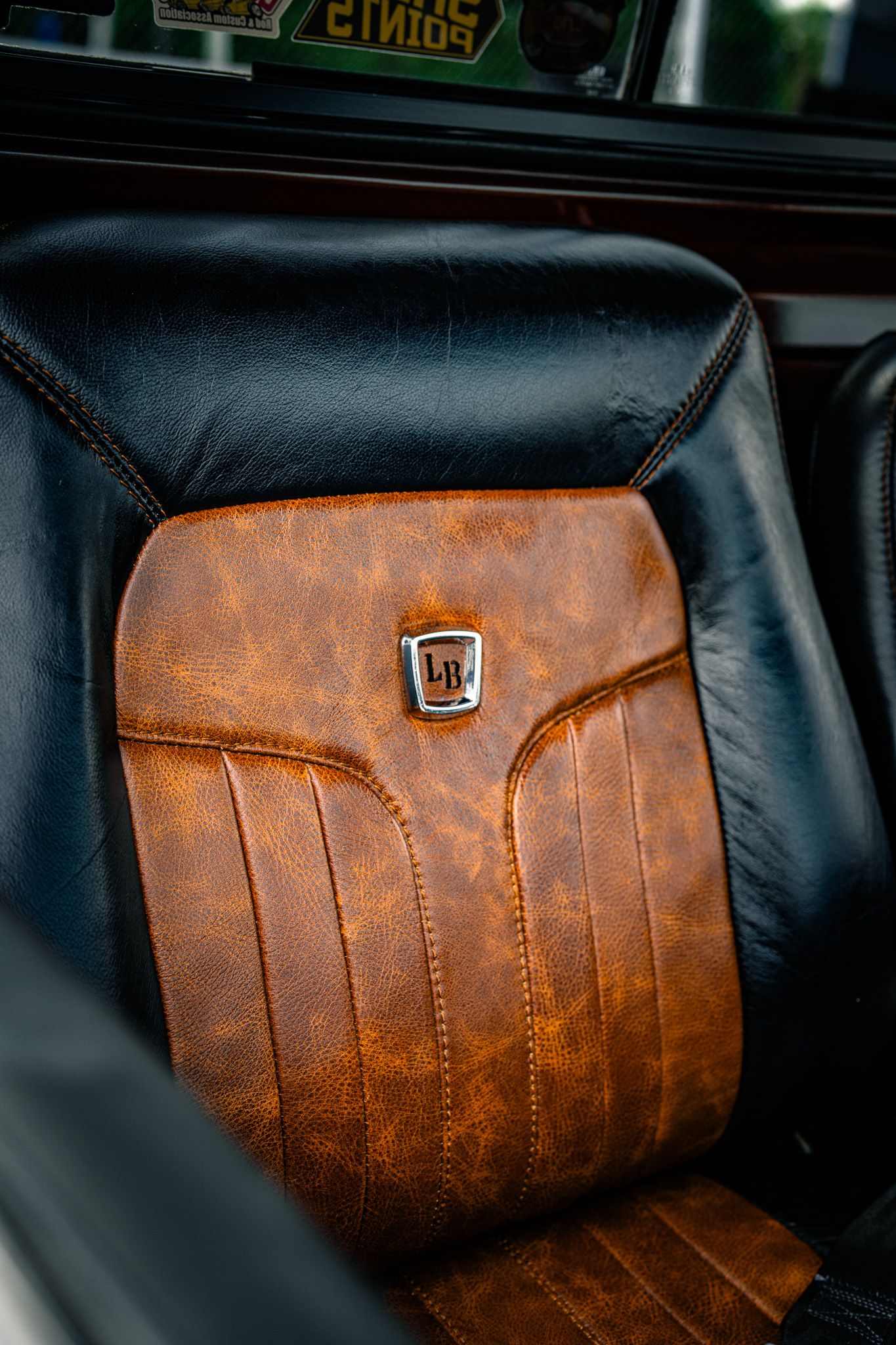 Vintage brown and black two-tone leather car seat with classic emblem badge detail. Southeastern Truck Nationals