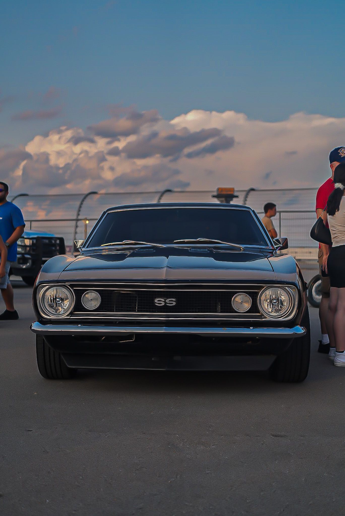 Classic black Chevrolet Camaro SS muscle car parked at sunset during an outdoor car show. Cars & Christ