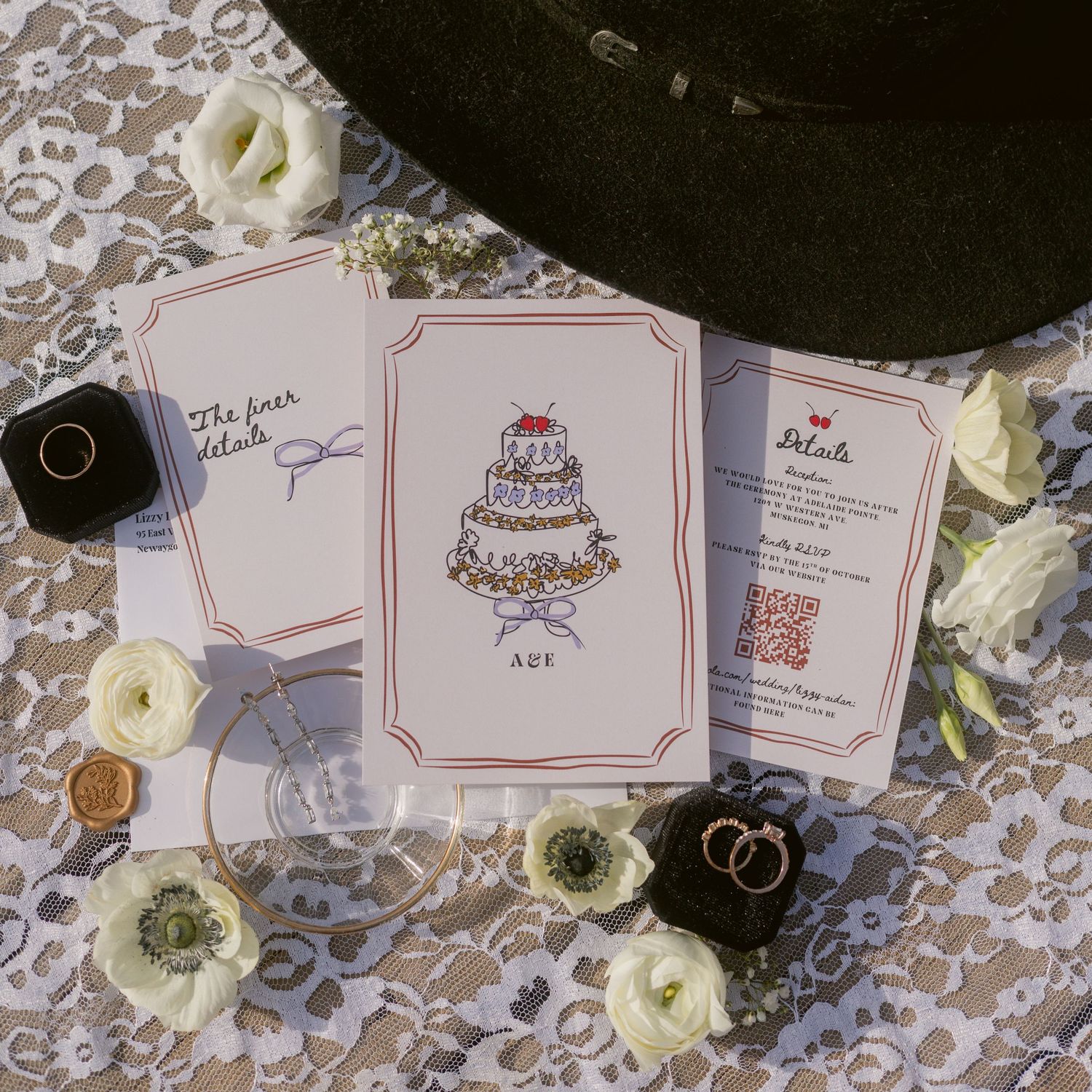 Elegant wedding stationery suite with illustrated cake design, details card with QR code, and floral accents on lace.