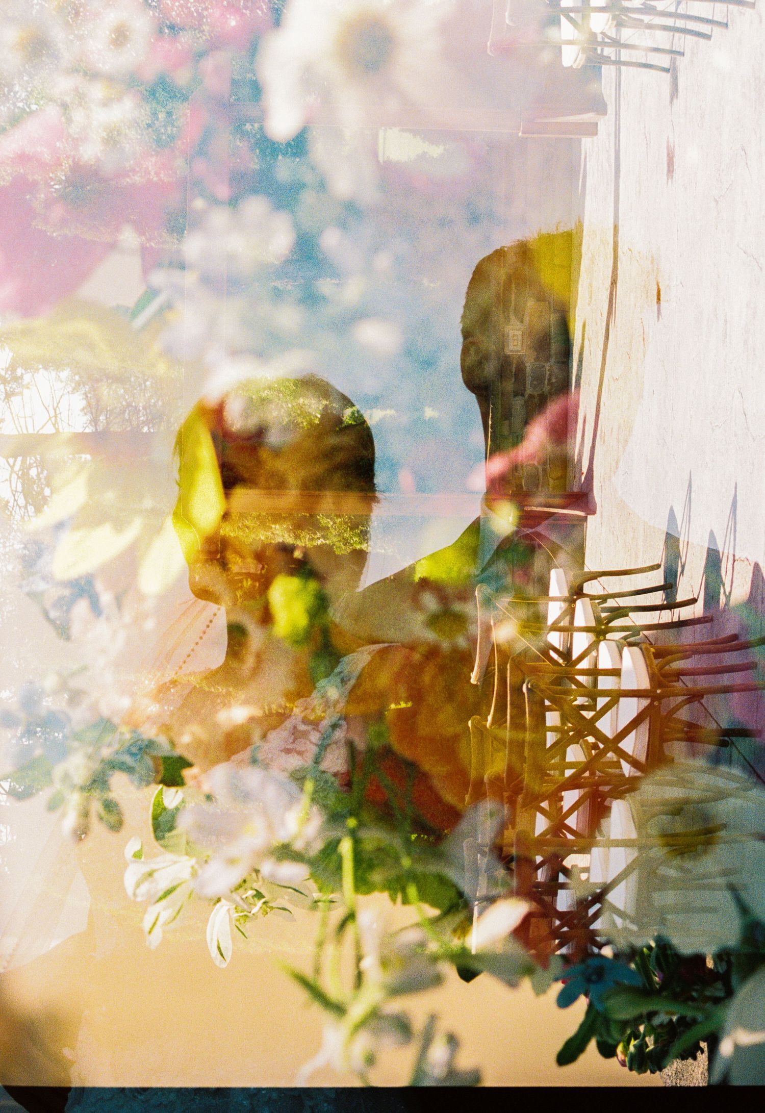 Dreamy double exposure wedding photo blending bride and groom silhouettes with soft floral bokeh in warm tones.