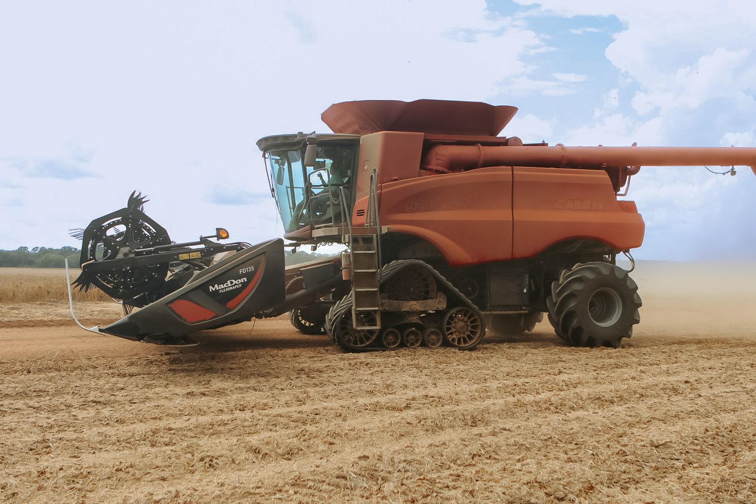 Large red Case IH combine harvester with header attachment operating in an open agricultural field.