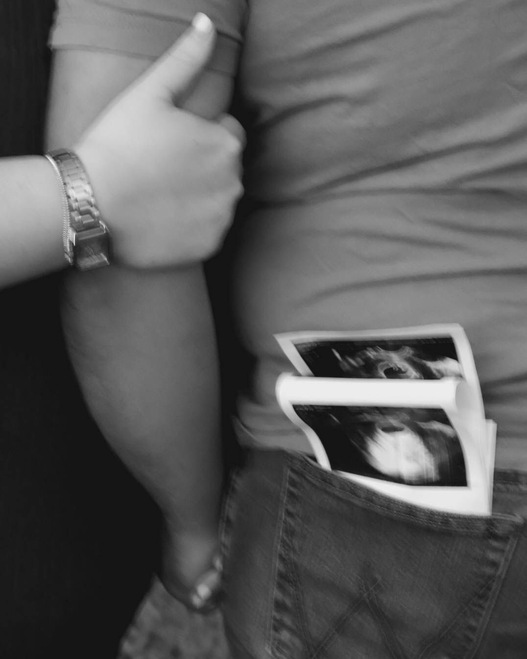 Series of black and white images showing ultrasound photos being tucked into a pocket.