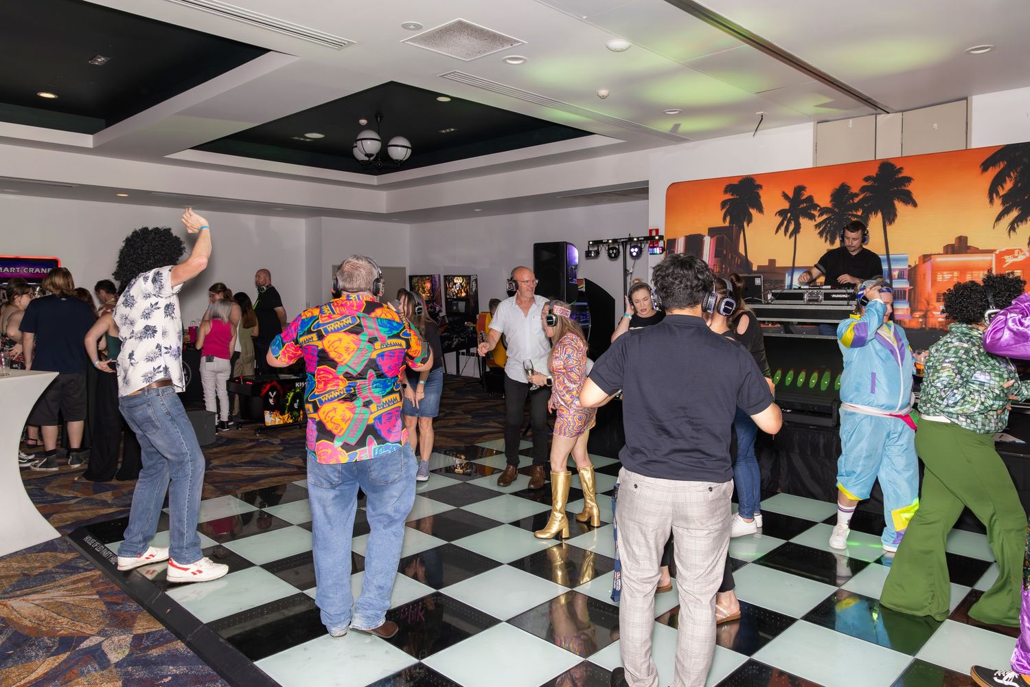 People dancing on a black and white checkered floor at a vibrant retro-themed party event.