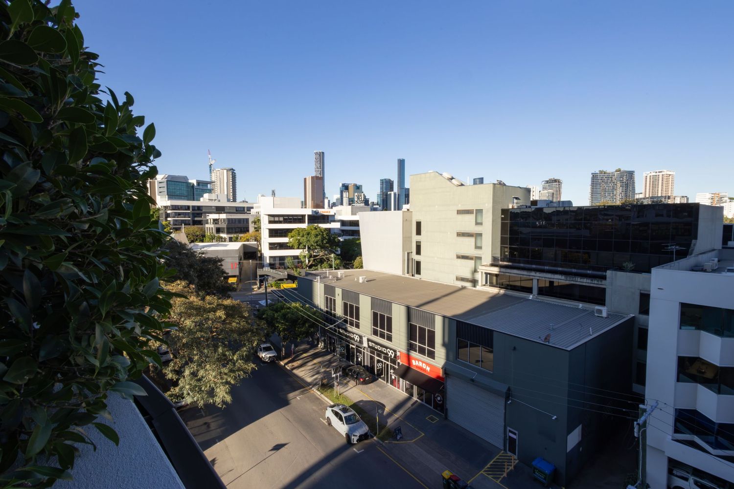 Aerial view of Brisbane city skyline with modern buildings and streets on a clear sunny day.