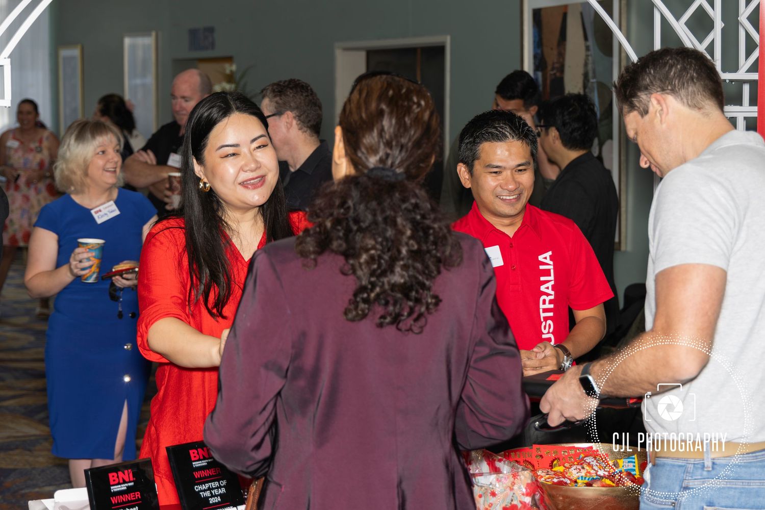 People networking and socializing at an Australia-themed indoor event, smiling and shaking hands in a lively gathering.