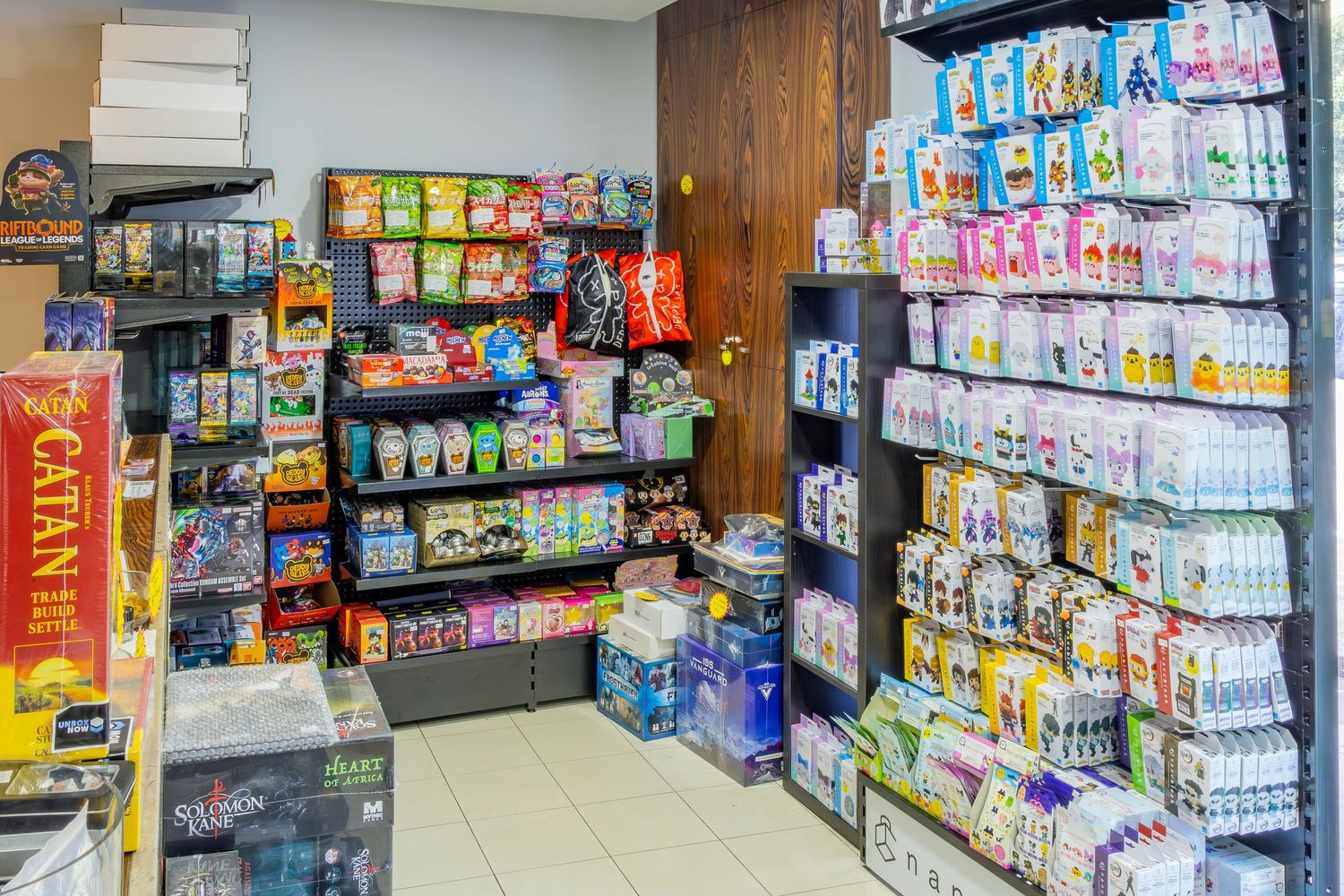 Retail store shelves stocked with colorful packaged goods, snacks, and household products in a small convenience shop.