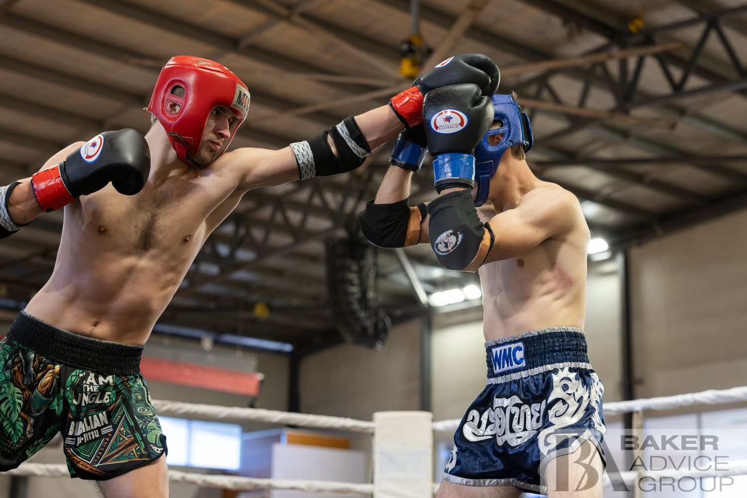 Two Muay Thai fighters sparring in a boxing ring, one throwing a punch while the other blocks during training.