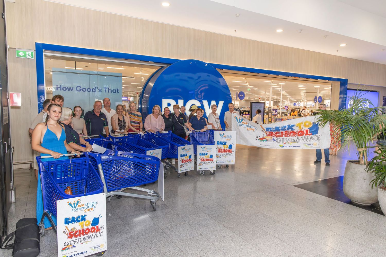 Group of people gathered outside a BIG W store entrance for a Back to School giveaway promotional event.