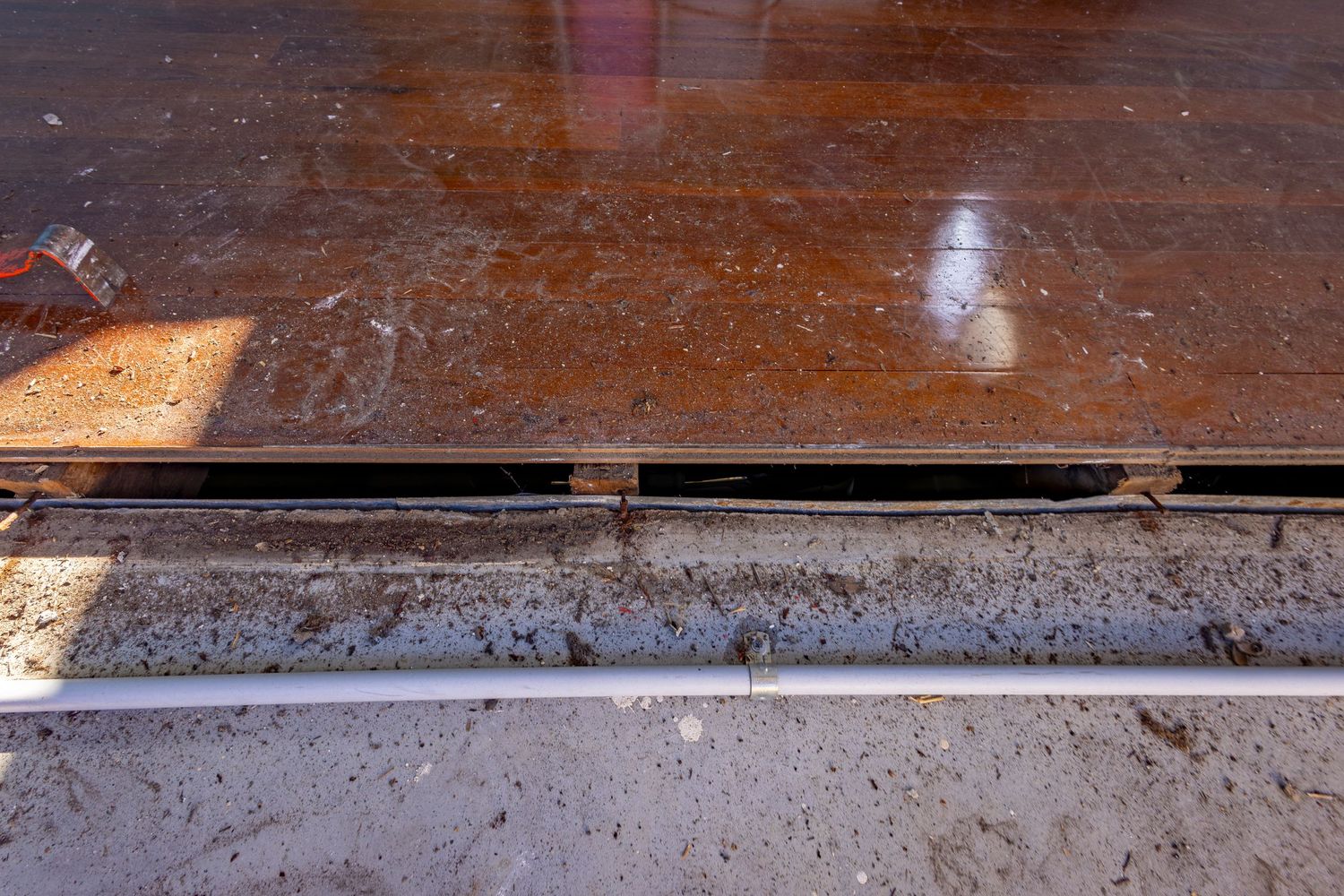 Close-up of a rusty metal plate resting on a concrete surface with a metal rail visible below.