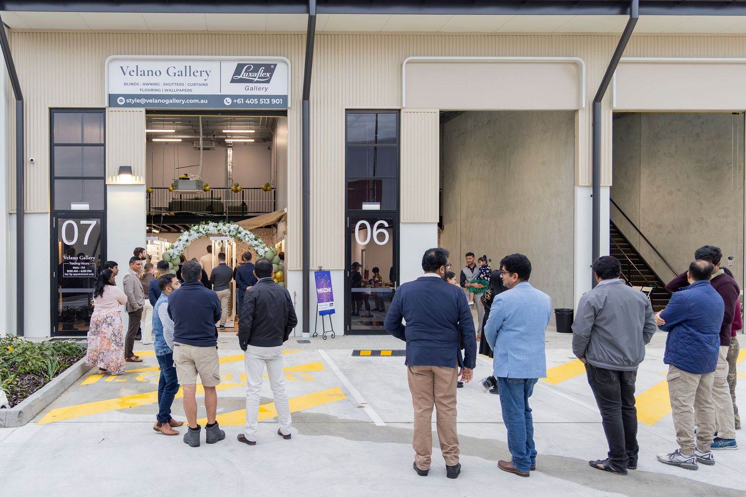 People gather outside Velano Gallery storefront units 06 and 07 during a grand opening event.