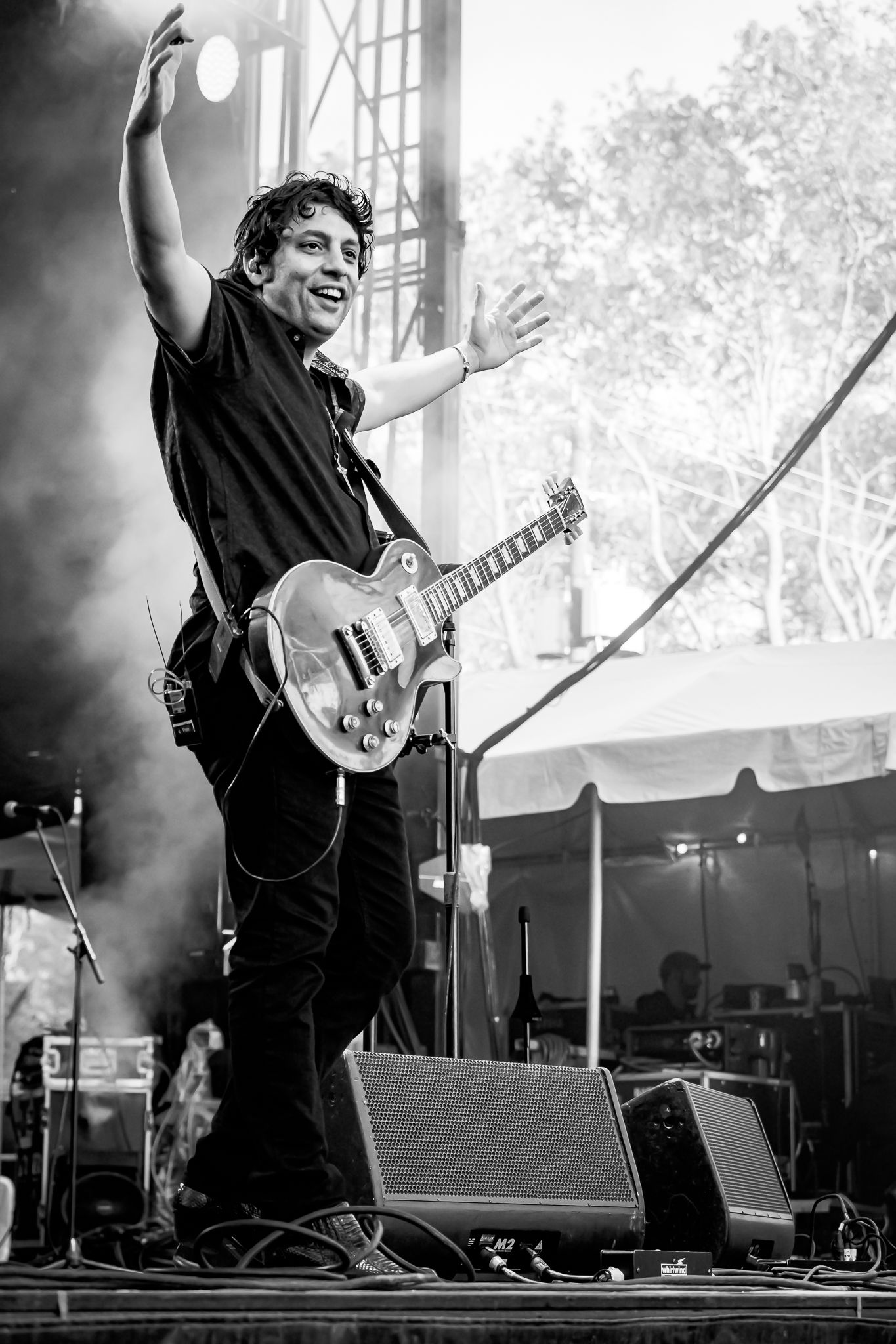 Male guitarist celebrating on stage with arms raised, black and white live concert photo.
