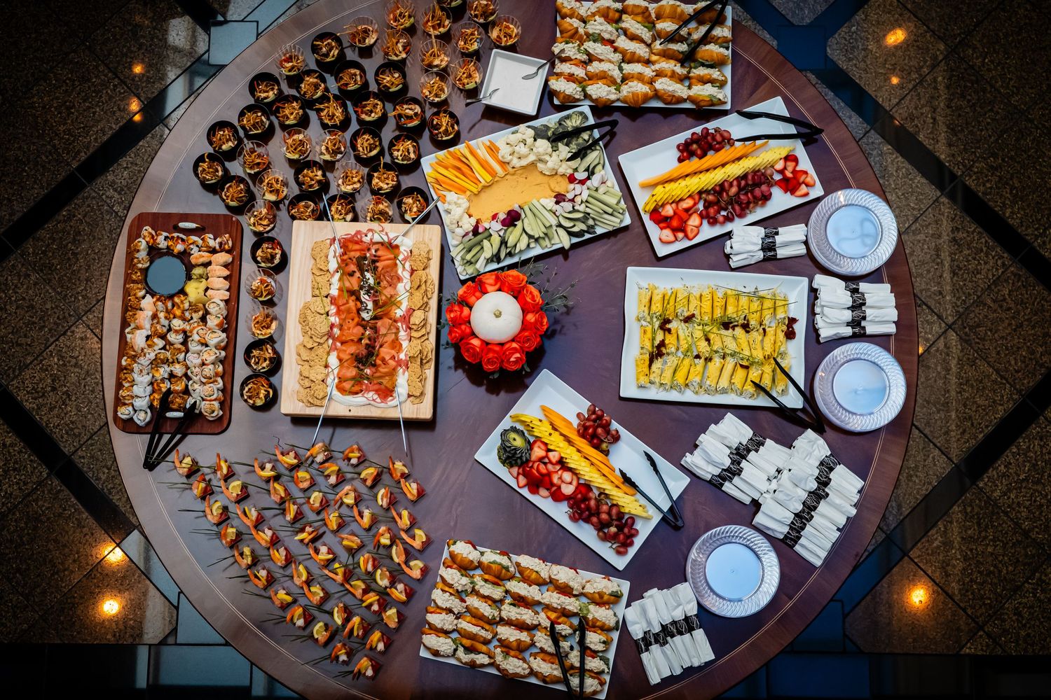 Aerial view of a beautifully arranged round catering table with assorted appetizers and finger foods.
