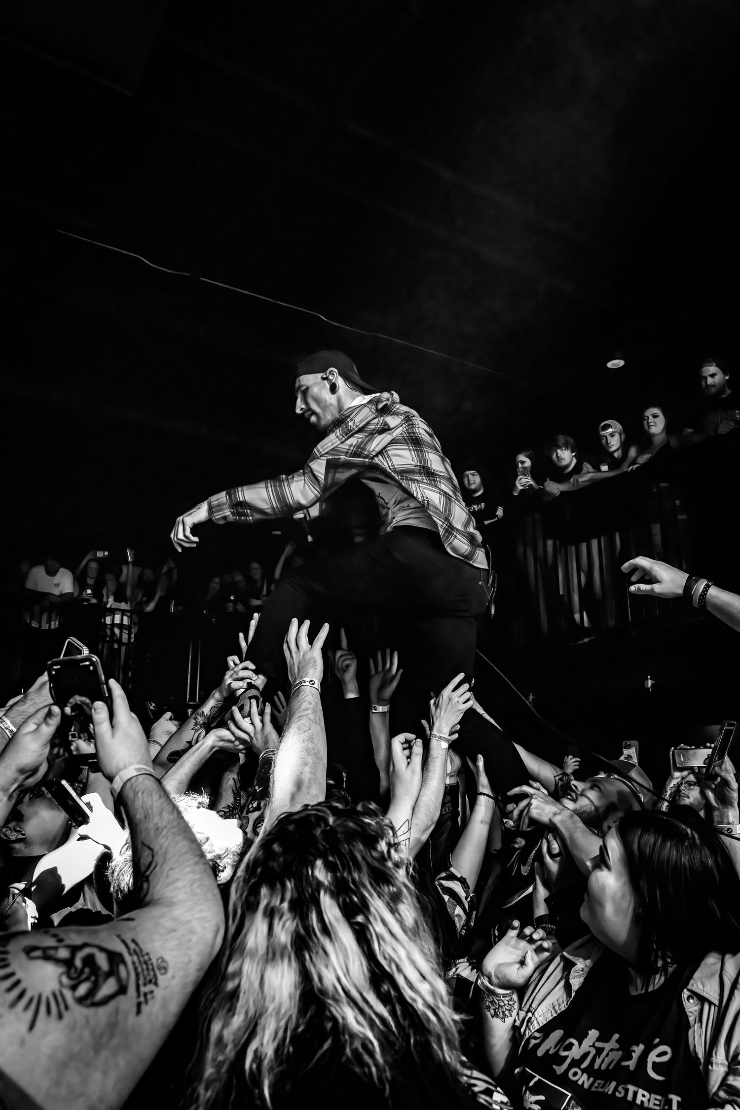 Black and white photo of a performer crowd surfing over an energetic audience at a live concert.