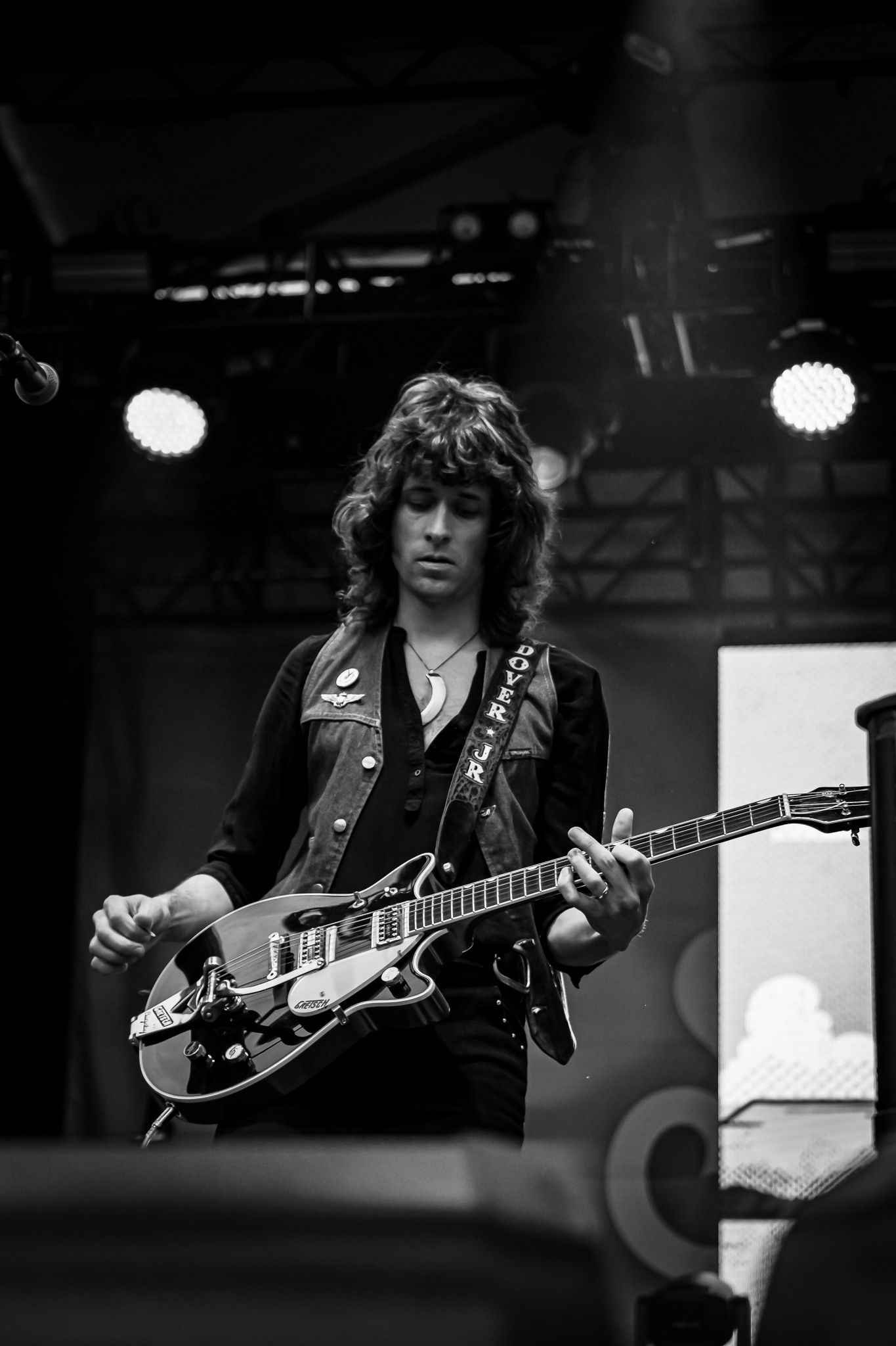 Black and white photo of a young male guitarist playing a semi-hollow electric guitar on stage.