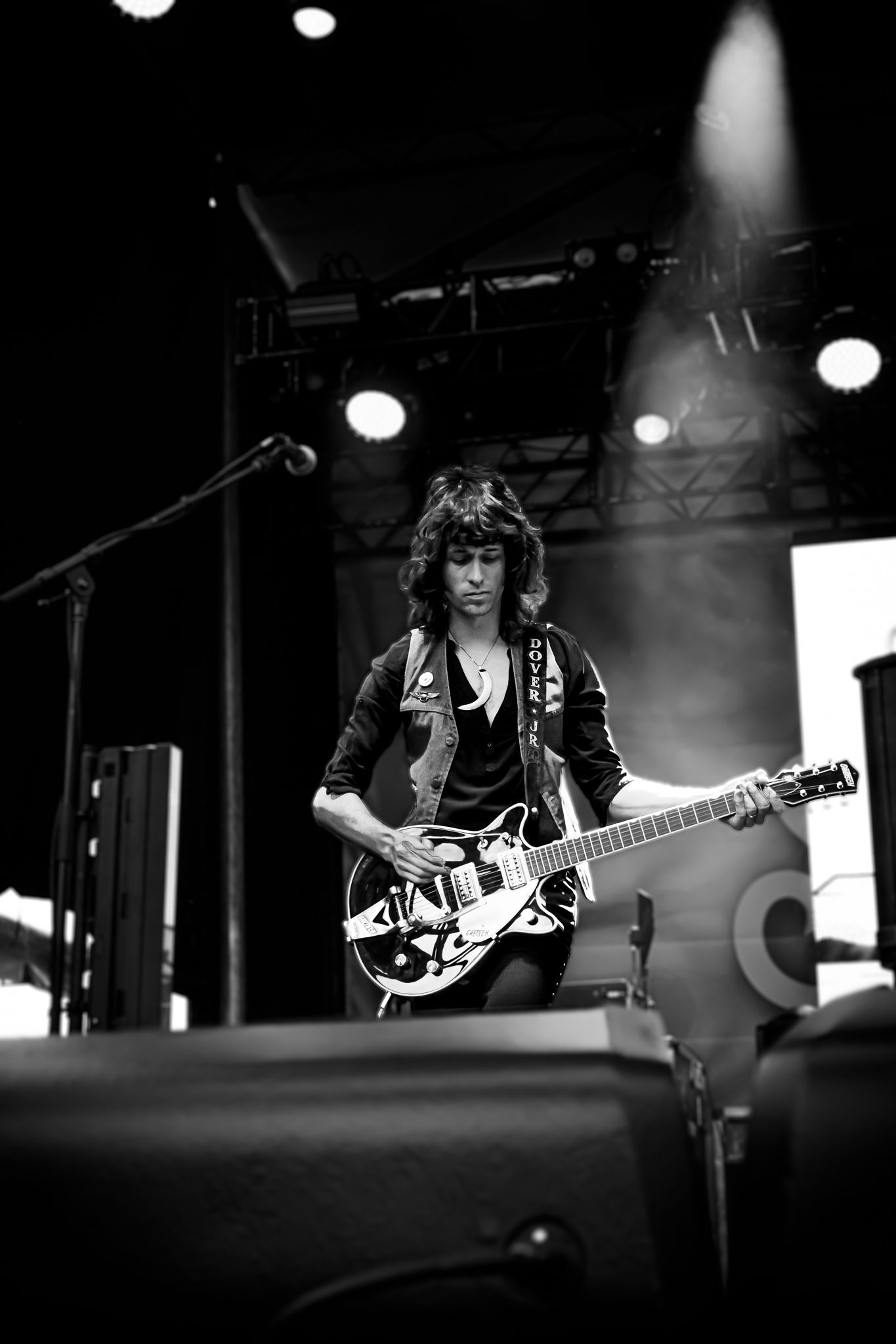 Female guitarist playing hollow body electric guitar on stage in black and white concert photo.