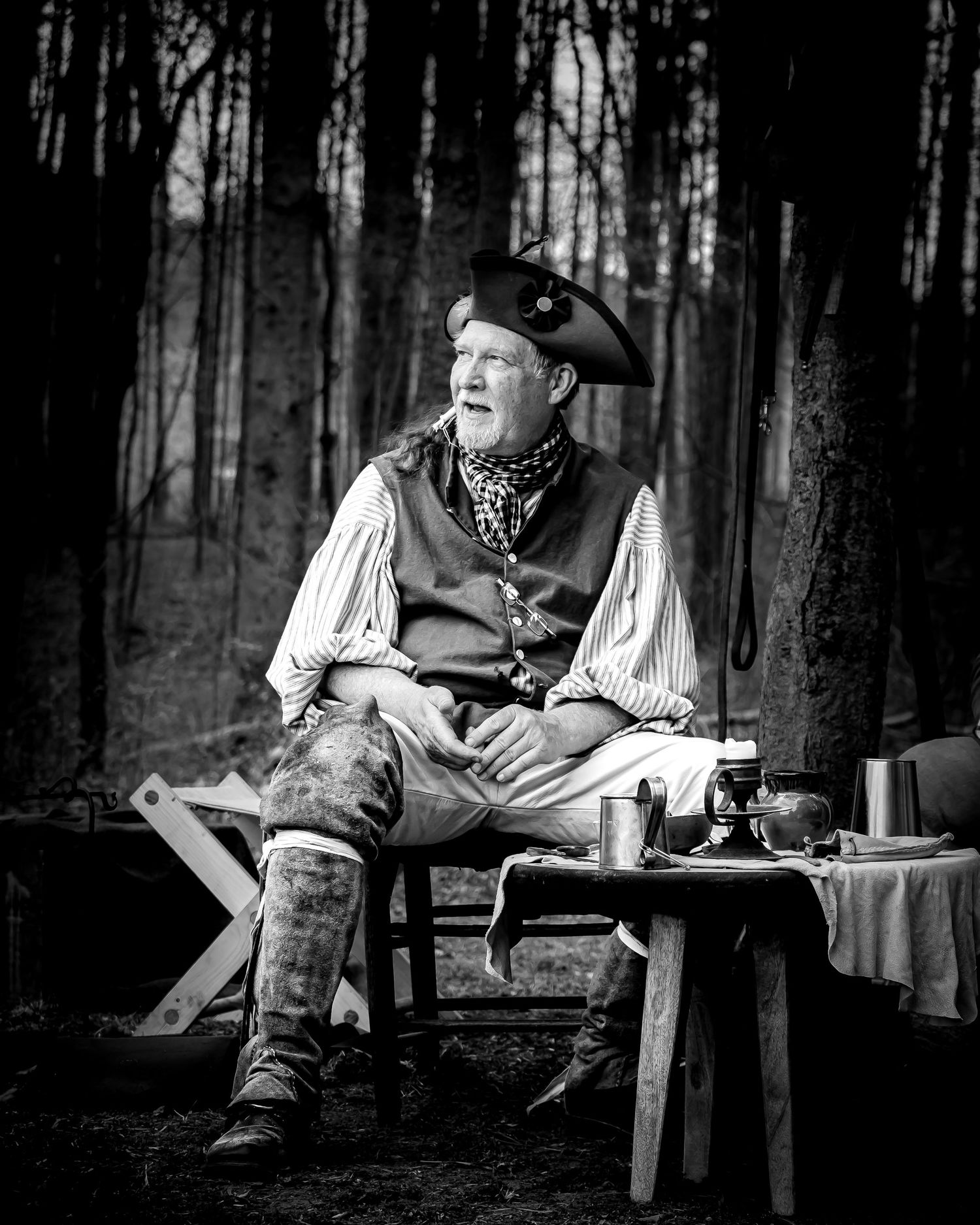 Black and white portrait of a man in colonial costume sitting at a wooden table in a forest setting Event Photographer Lavonia North Georgia