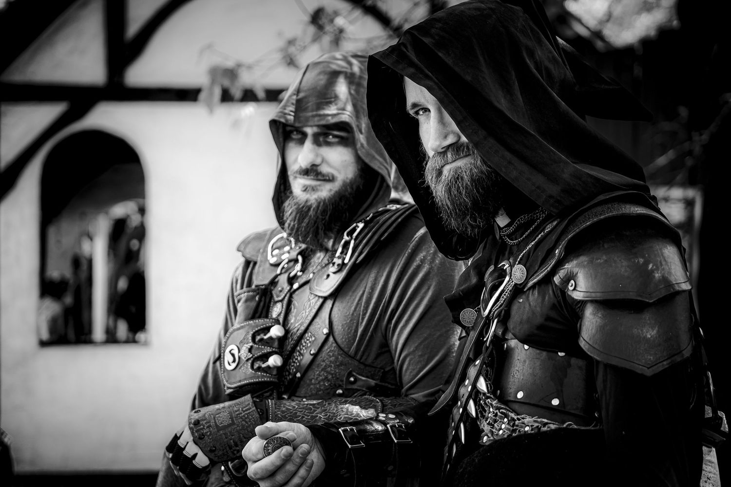 Two bearded men in medieval armor costumes pose in black and white at a Renaissance faire.