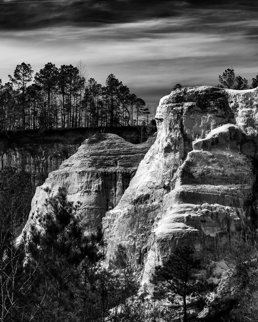 Dramatic black and white layered sandstone rock formations with pine trees above. Black and White Photography Fine Art Photography