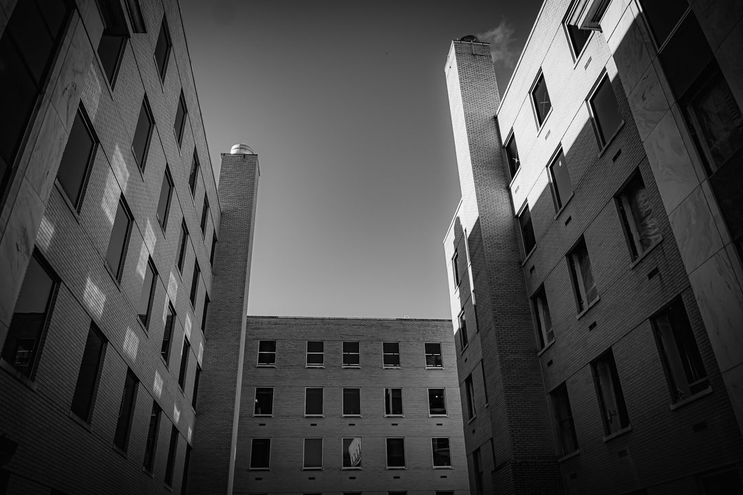 Low angle black and white photo looking up at modern urban buildings against a clear sky.