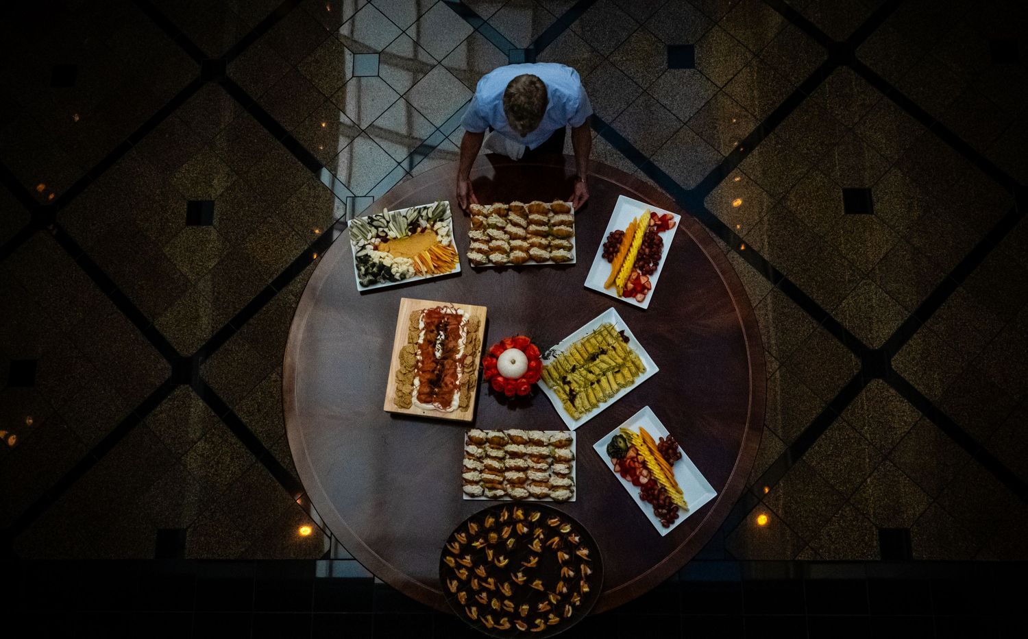 Overhead view of a round table with elegantly arranged catering platters and appetizers at an event.